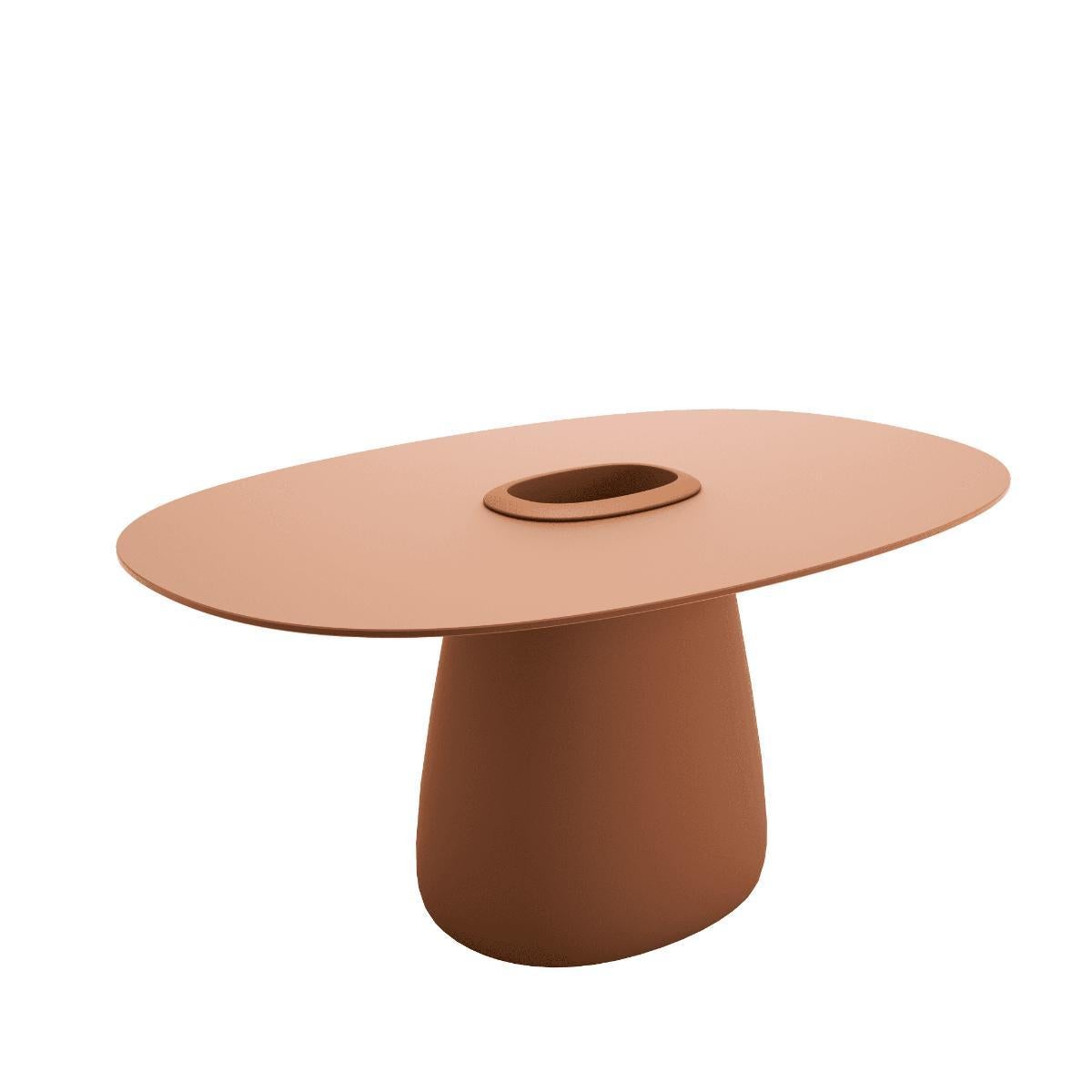 La Cobble Table conçue par Elisa Giovannoni se caractérise par une base centrale où l'on peut insérer un seau contenant des plantes ou de la glace pour conserver les bouteilles au frais. Le plateau de table fin est fourni dans des matériaux adaptés