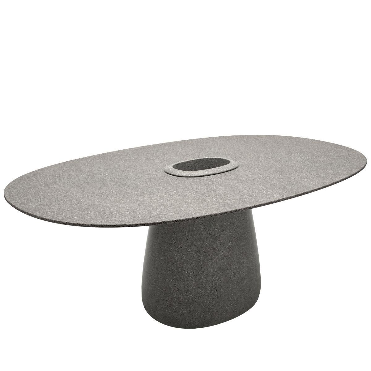 La Cobble Table conçue par Elisa Giovannoni se caractérise par une base centrale où l'on peut insérer un seau contenant des plantes ou de la glace pour conserver les bouteilles au frais. Le plateau de table fin est fourni dans des matériaux adaptés