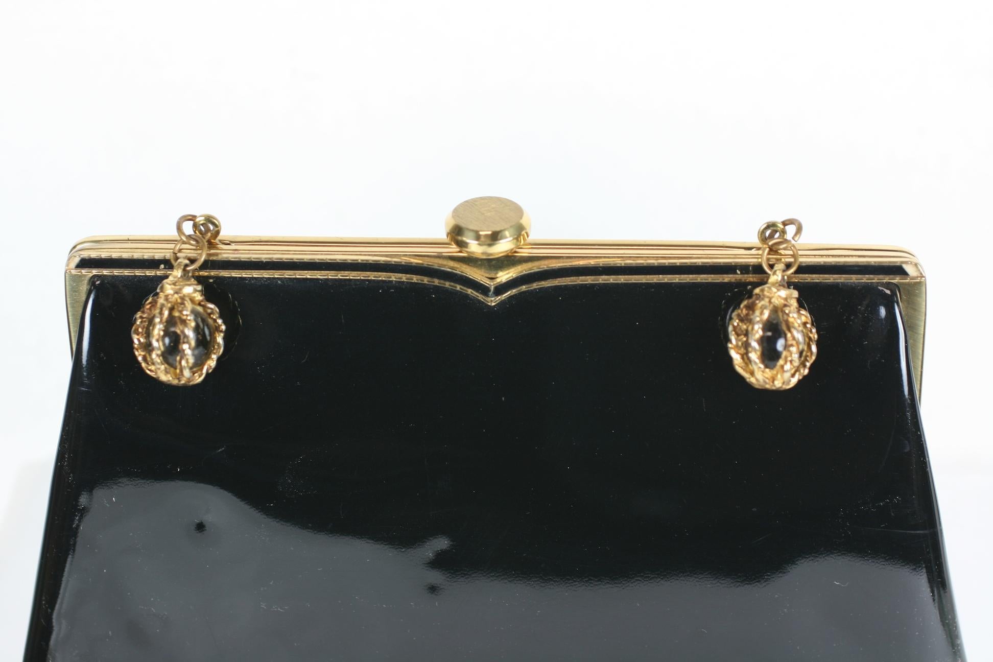 Coblentz Patent Clutch with Glass Orb Charm decorations which can be folded inside to use as well as a plain black clutch with enamel frame. 1950's USA. Does not appear to be used. Has original mirror and change purse. 
9.5