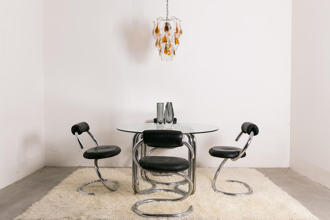 Mid-Century Italian dining table set with four 'Cobra' chairs designed by Giotto Stoppino, 1970s, Italy. The chairs are made from tubular finished in chrome metal, winding from the base to the seat and backrest. The seat and backrest are in black
