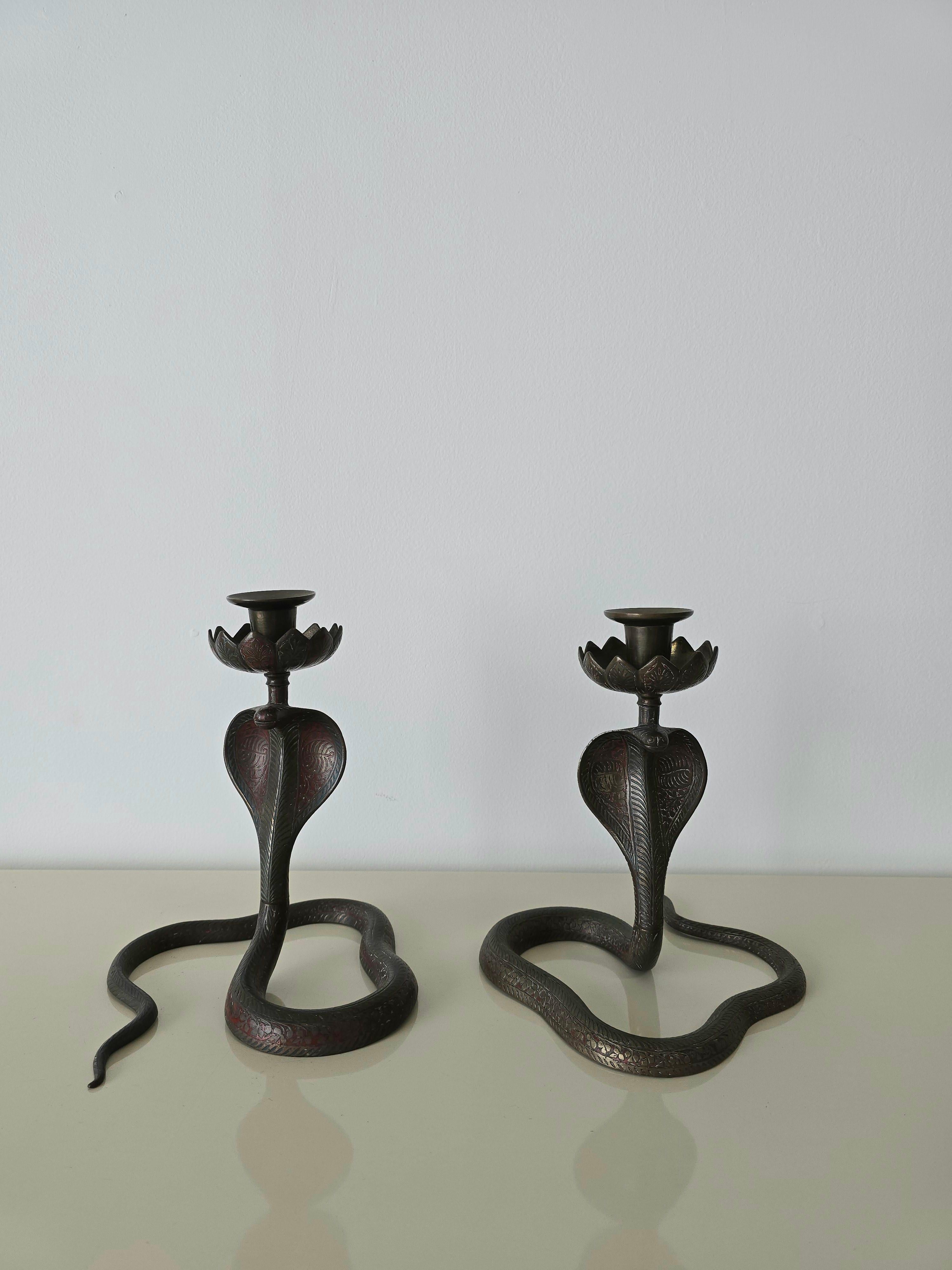 A pair of Cobra snake shaped bronze candleholders. Made in the 1950s. This pair features a motif throughout the body of the snake shaped candle holders. Its made in bronze material and features dark red colouring. They can be disassembled into a few