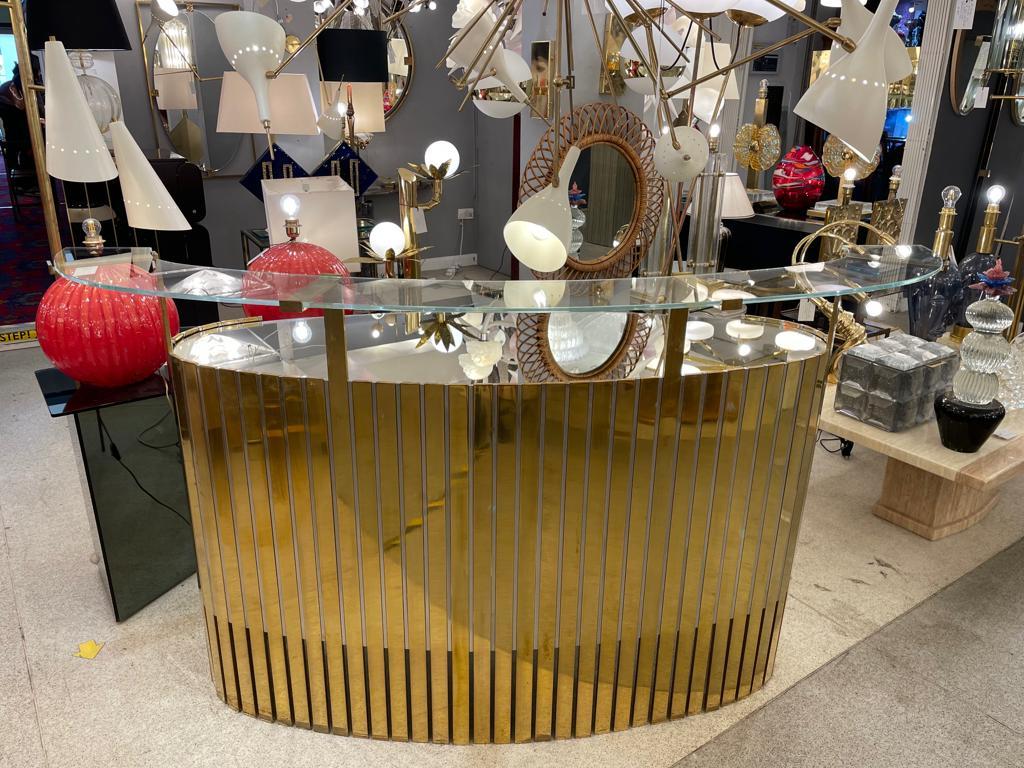 A beautiful demi-lune cocktail bar. The core is made out of stainless steel and brass, whereas the two tops are made of mirror. The internal side has an open space with a useful shelf.
