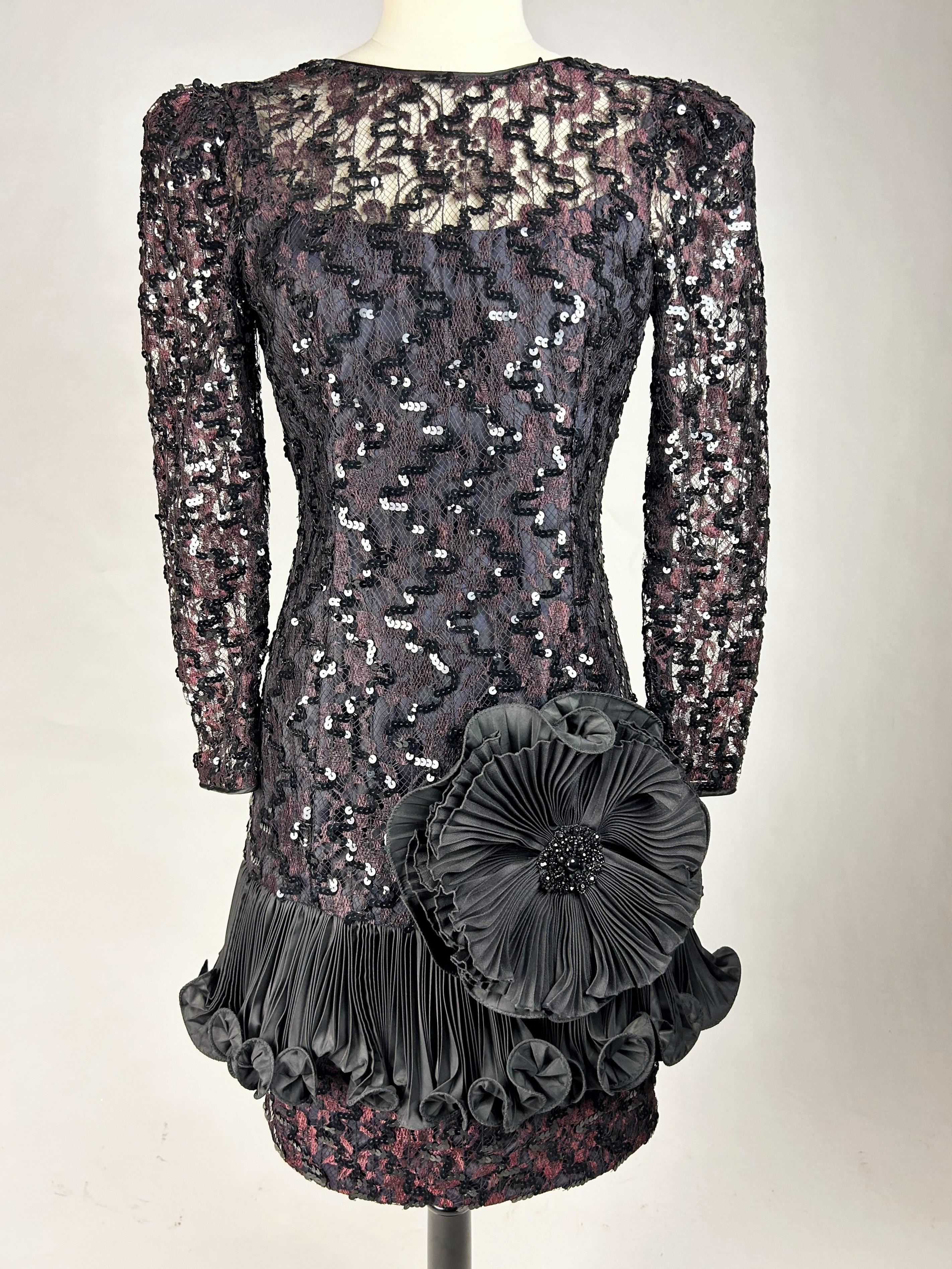 Circa 1985

France

Black and wine lace cocktail dress embroidered with sequins by Louis Féraud Haute couture dating from the 1980s.  Short, form-fitting sheath dress with long sleeves and plunging neckline in the back fastened with a zip. Large