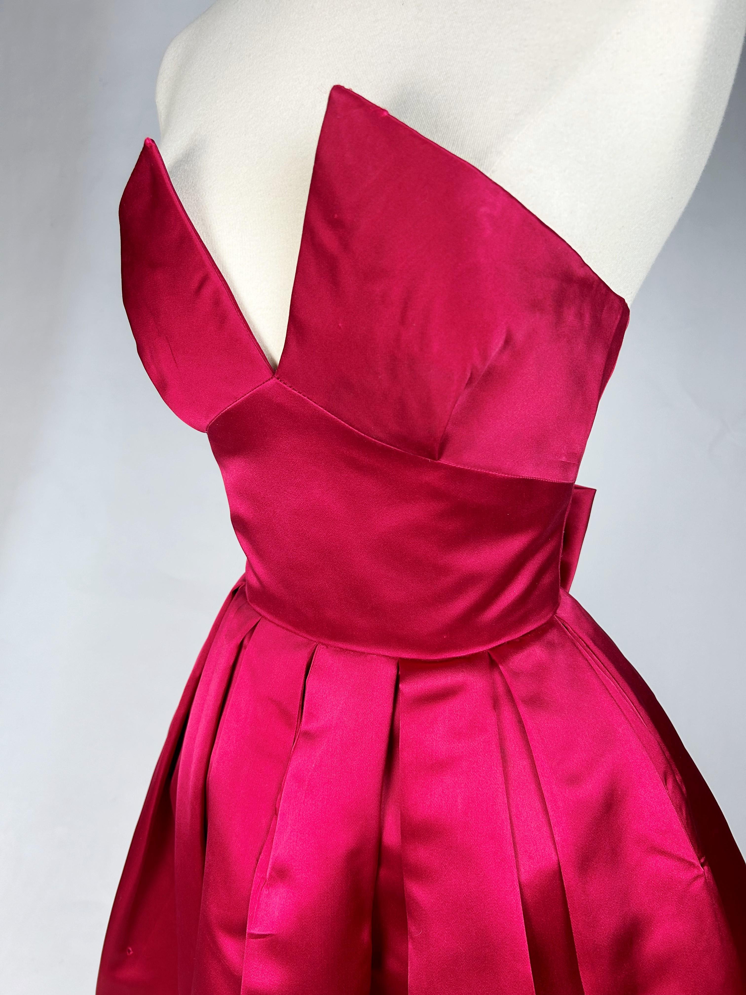 Circa 1955

Paris

Raspberry satin cocktail dress by Claire Comte, 17 bd des Capucines Paris, dating from the 1950s. In the style of Christian Dior, this bare-back dress with plunging neckline forms two points on the bust and the tight, openwork