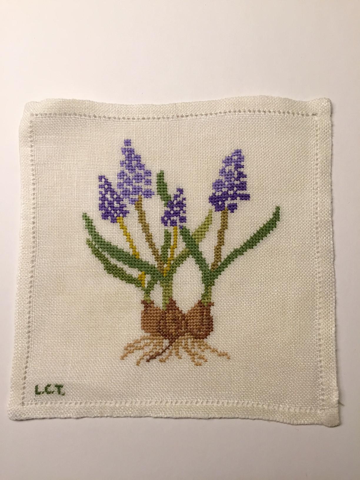 This set of eight cocktail napkins is beautifully hand embroidered with flowering spring bulbs. The needlework for the flowers is done in shades of lavender and bright yellow with green and brown for the stems and bulbs.  The maker embroidered his