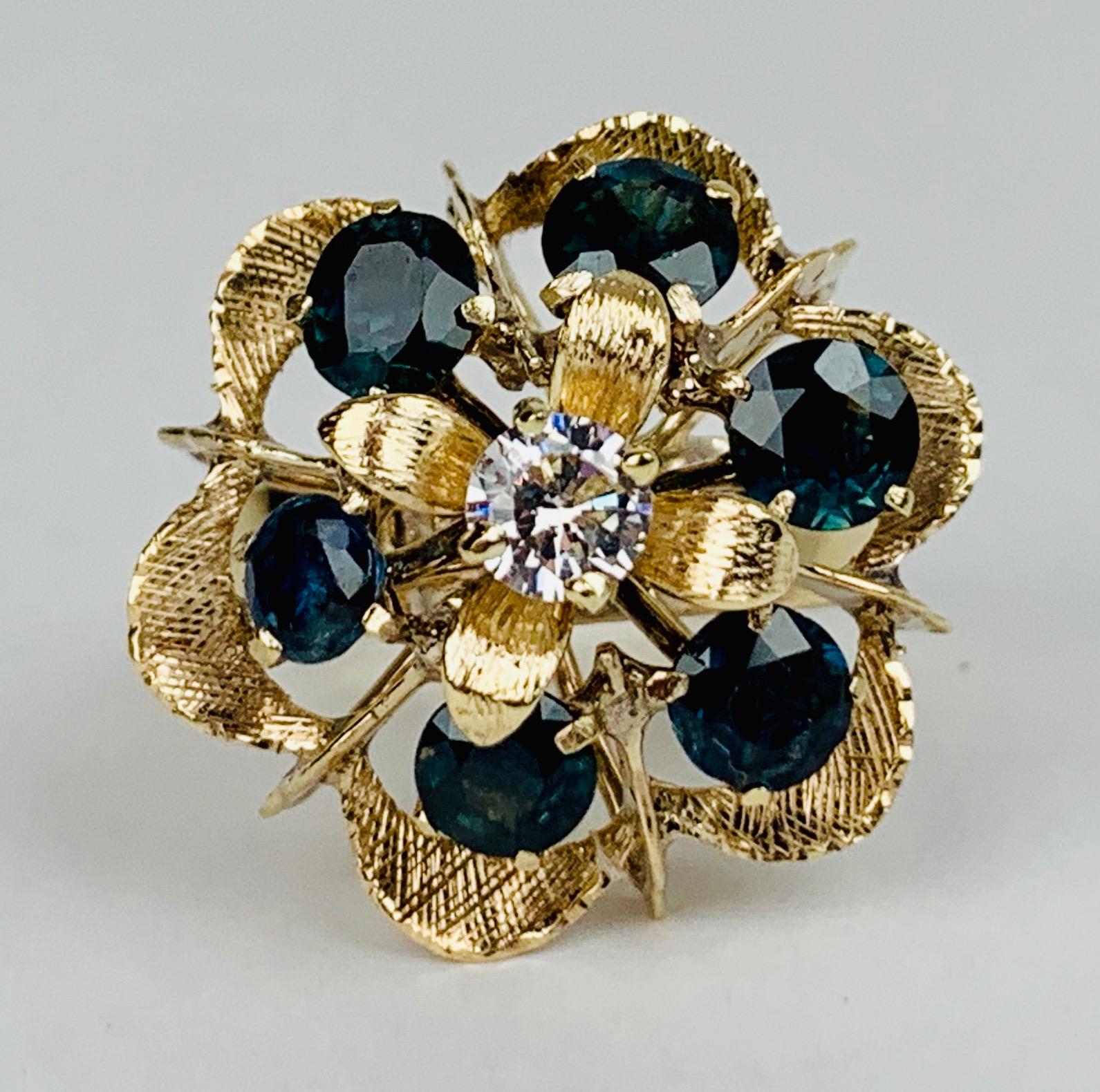 A 1960's cocktail or cluster ring with six sapphires and one cubic zirconia set in 18k yellow gold.  The ring retains its original Florentine finish on the setting.  

This ring can be resized.
Professionally cleaned and polished.
Size 5.5