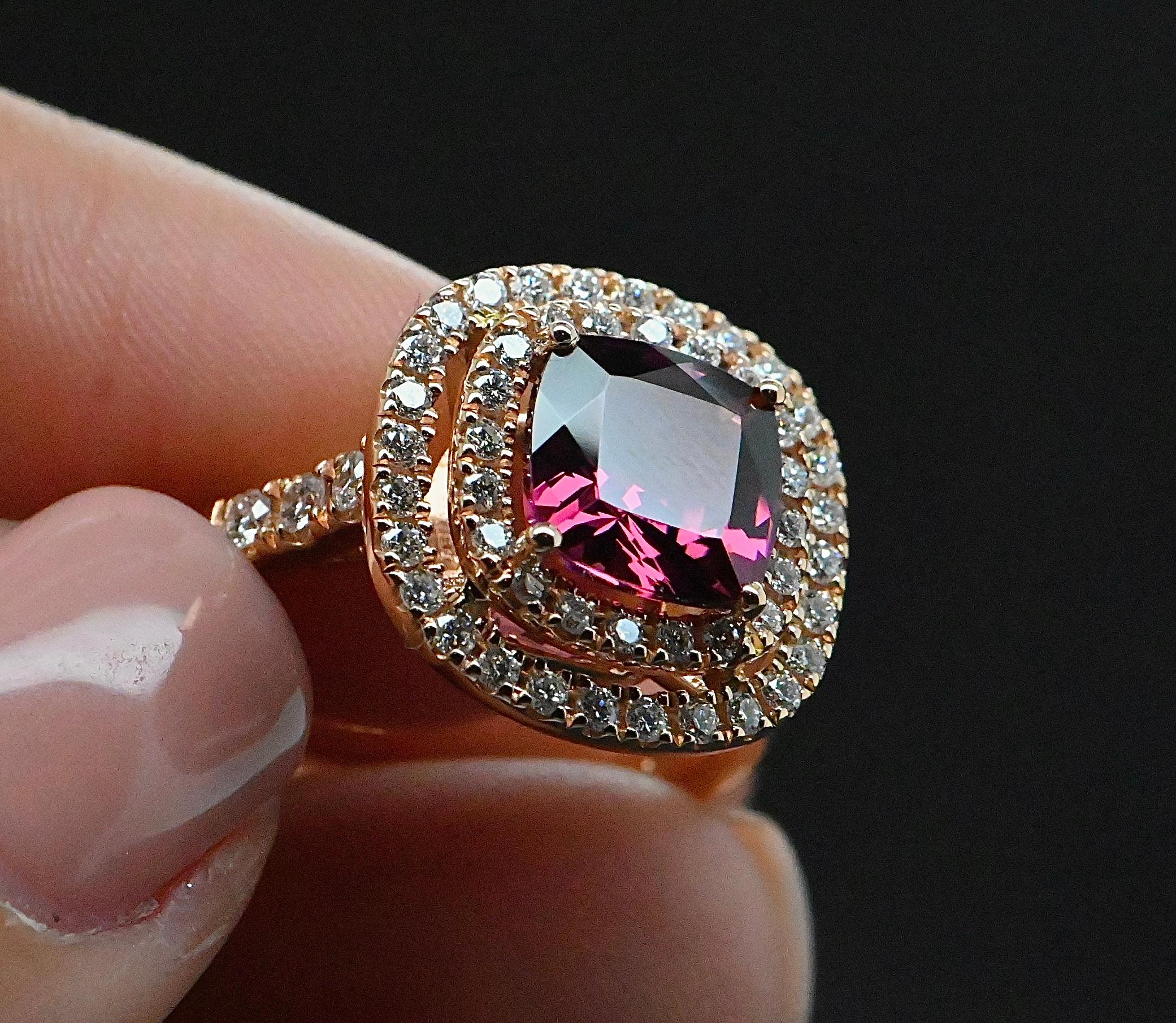 Questo delicato anello da cocktail in oro rosa 18 carati è l'epitome dell'eleganza. Al centro, una superba rodolite taglio cuscino di 2,550 carati irradia un tenue bagliore. Questa gemma, dalla brillantezza profonda e accattivante, è armoniosamente