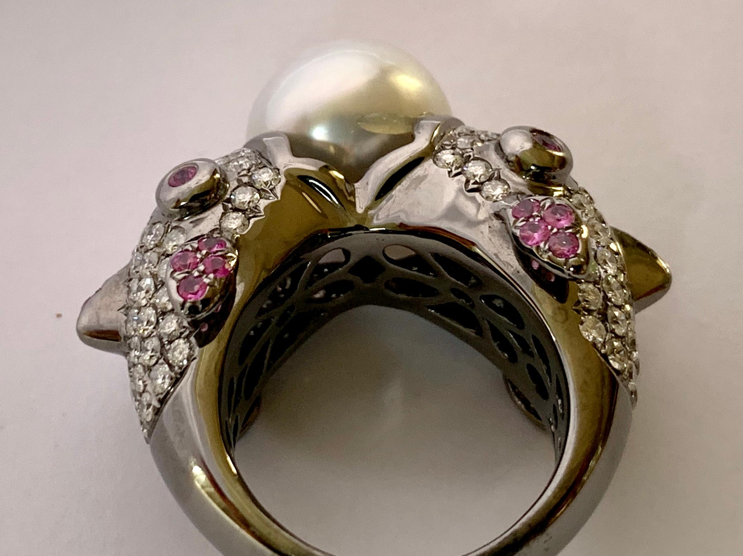 This unique Ring features one white South Sea Pearl (13,8mm) wich is held by 2 Fishes from each sides. Pave set with 138 brilliant cut Diamonds of 2.94 ct and 24 pink Sapphires weighing 0.59 ct. In 18 K white Gold with black Rhodium. 
The ring is