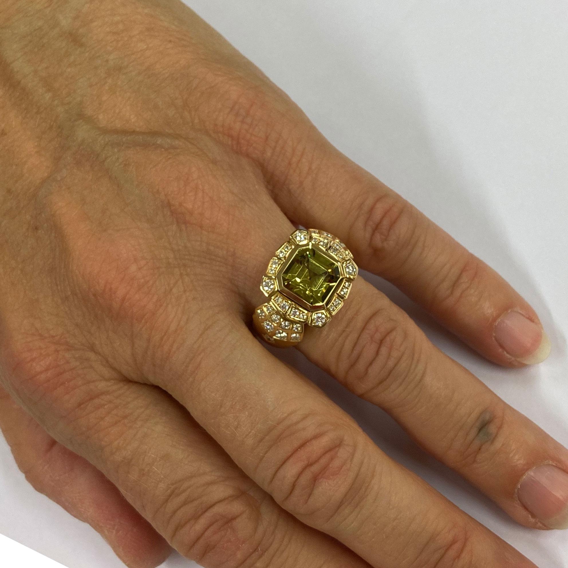 This Cocktail Ring in Rose Gold 18 kt with a slightly lifted center part shows a bezel-set , Asscher cut, green Garnet ( Andradite) with a total weight of 4.24 ct. The intriguing green color of the gem is highlighted by an intersected and