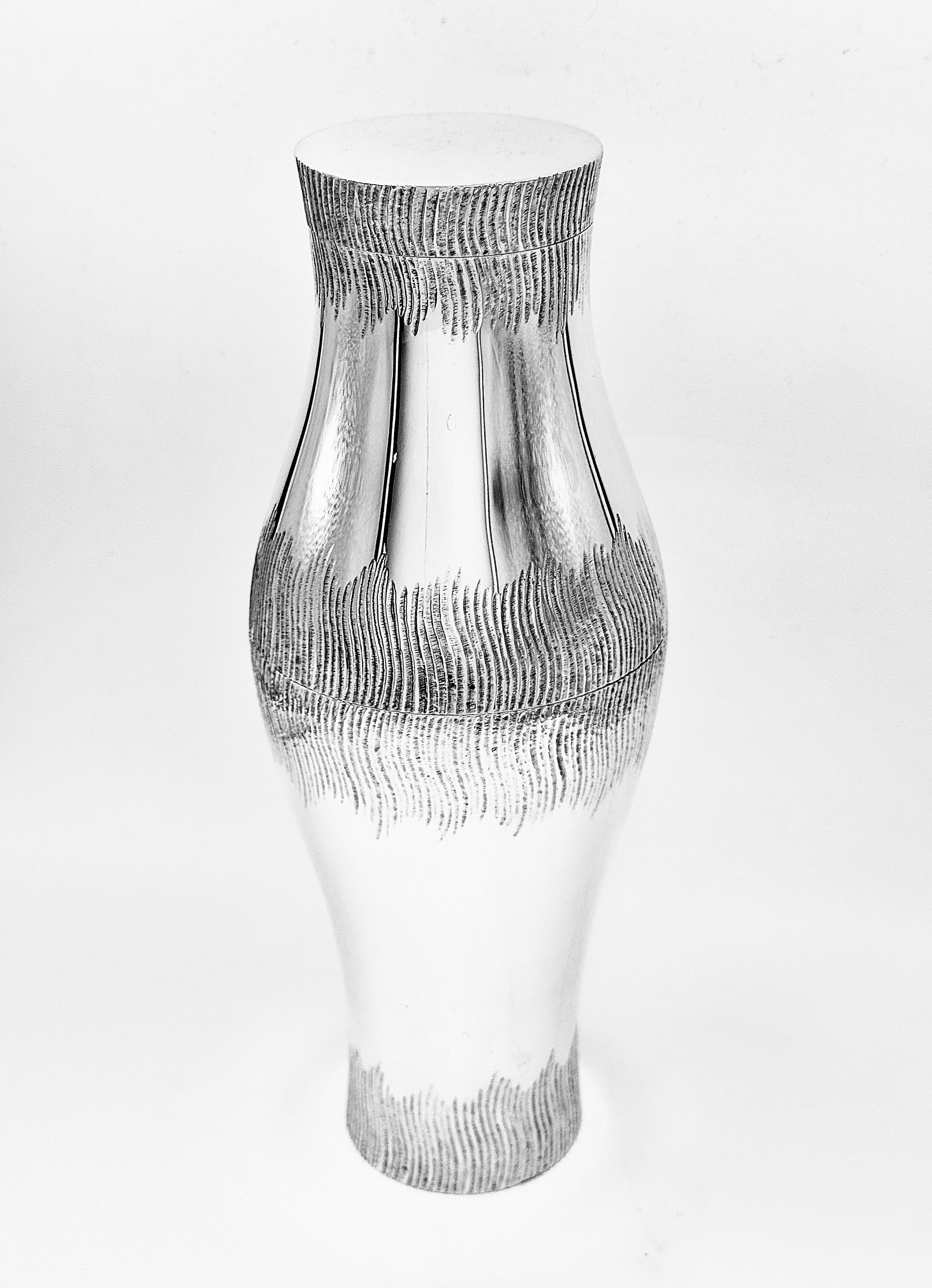 A wonderful and unusual sterling silver cocktail shaker made by Grant Macdonald, in London, and dated 1979. The elegantly flared body is finely hand chased with a textured, wave-like pattern encircling the upper and lower sections, creating a