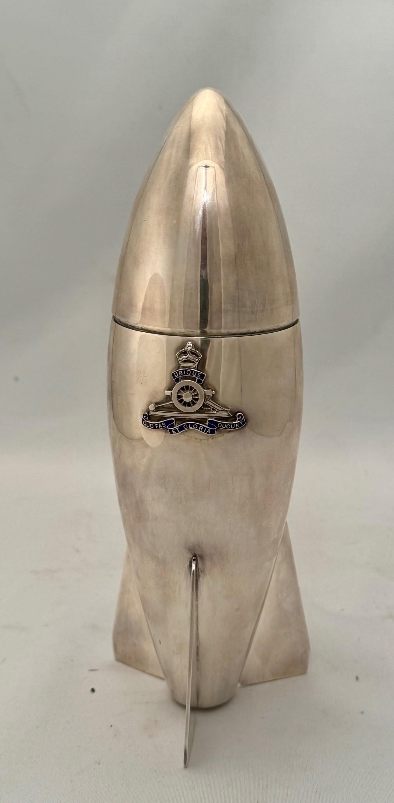 This very stylish Cocktail shaker made by Dixon& Son variously described as being from the 1930s 40s 50s by  sellers. Its slender shaped body and fins are further decorated with the crest of the Royal Artillery UBIQUE (Everywhere) and QUO FAS ET