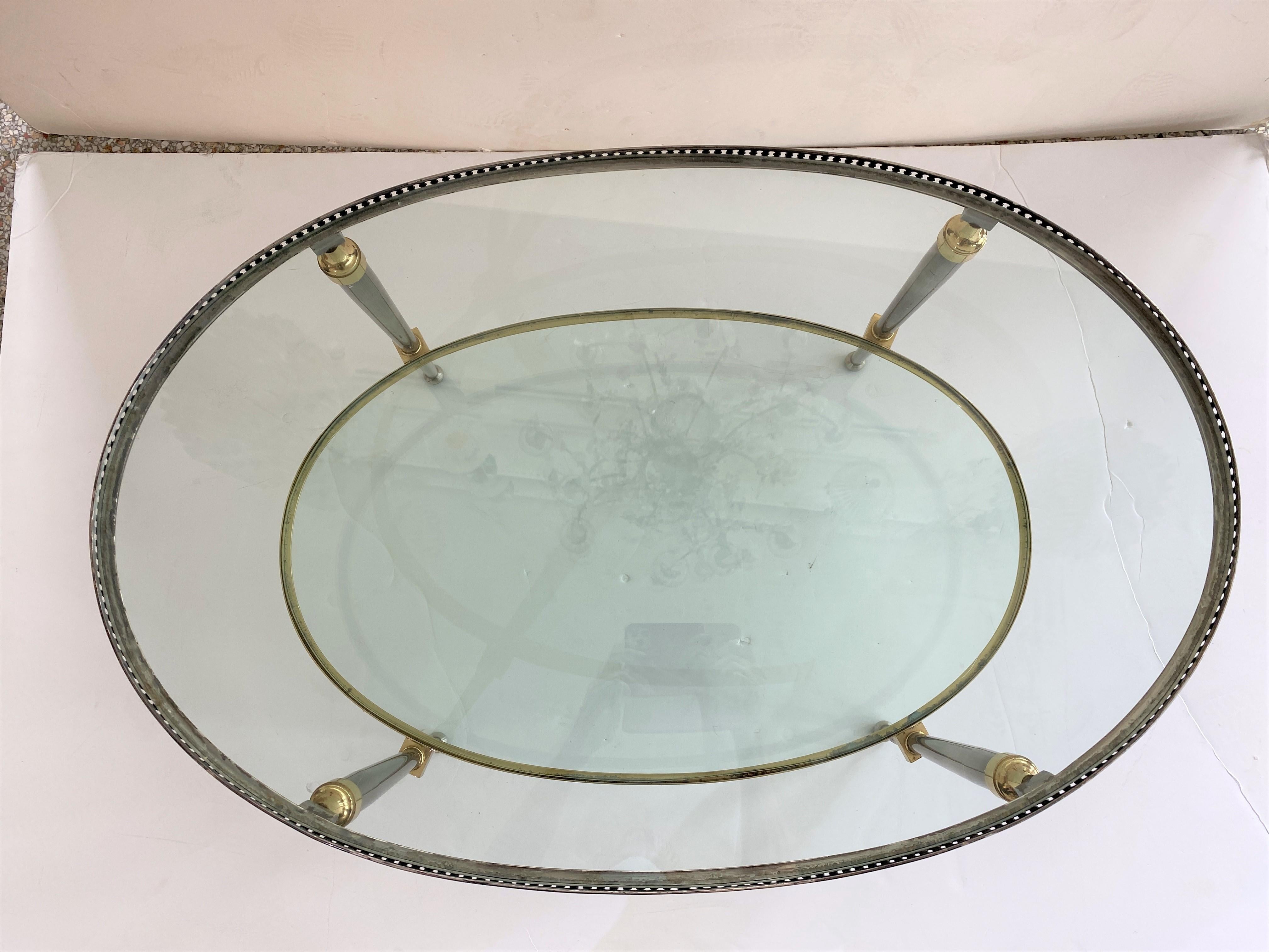 This stylish campaing style, oval-form, two-tiered cocktail table dates to the 1960s-1970s and was designed and fabricated by the American firm of Trouvailles of New York City. The piece is fabricated in patinated steel, brass and glass.

  