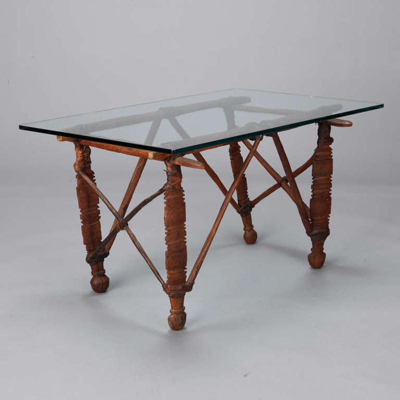 Glass topped cocktail table with circa 1890s base made from hand-carved wooden North African elements bound with leather. 

Measures: Base Only: 34.5” W x 21.4” H x 35” D

Top Only: 38.5” long x 24” wide x .5” depth.