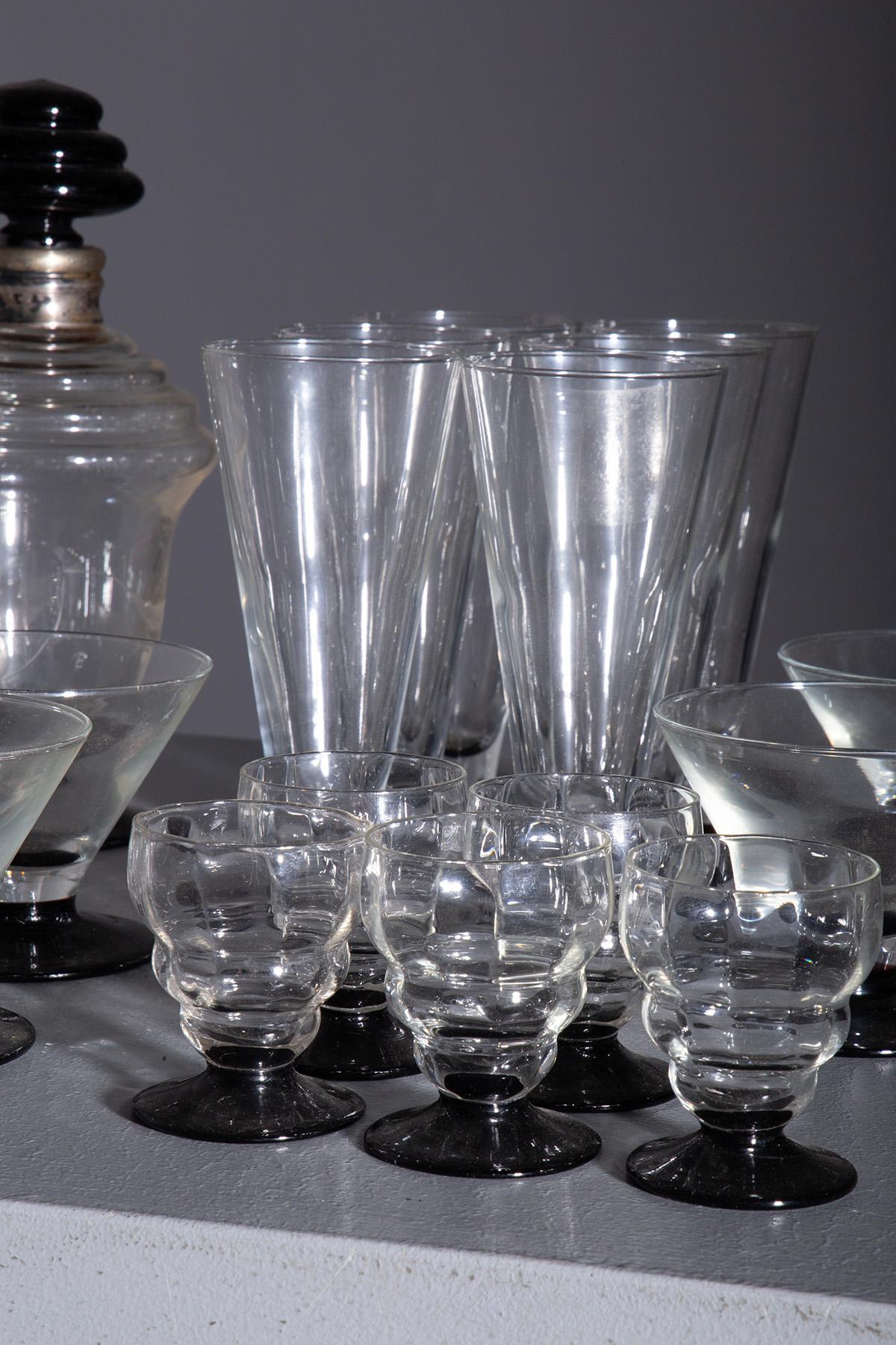 French cocktail set from the 1980s 'Kyoto' series by Luminarc . Consisting of bottle, 5 small cognac glasses, 6 flutes, 6 cocktail glasses, characterized by the striking contrast between the dark bases and the transparent glass, creating a refined