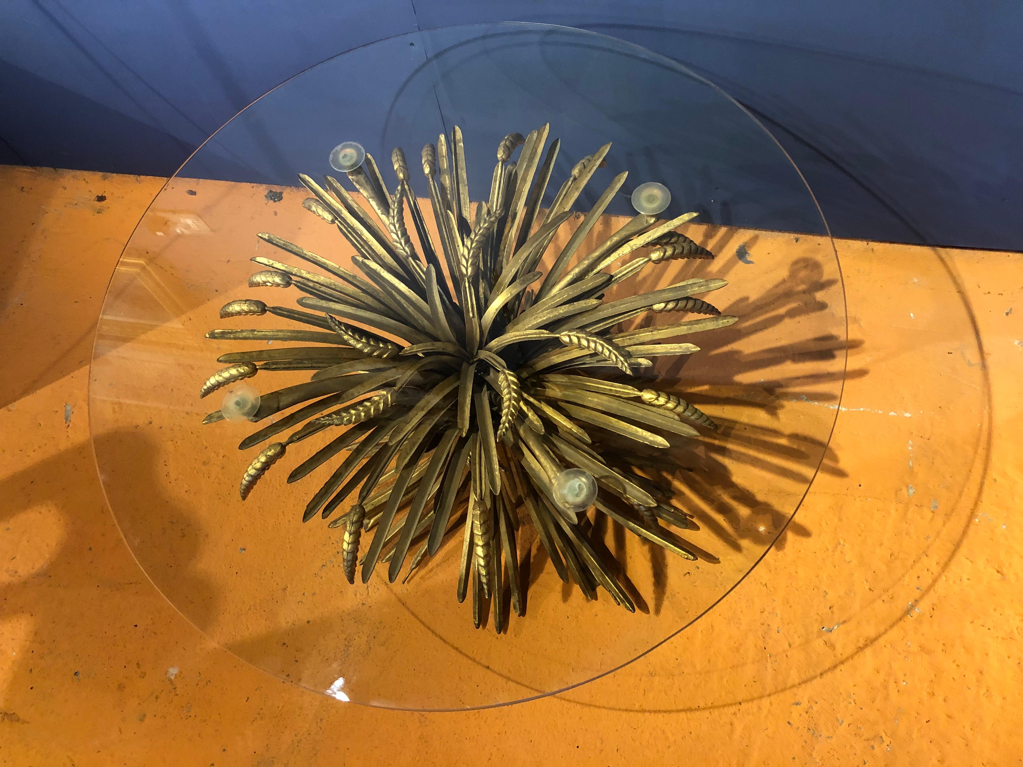A gilt metal sheaf of wheat tied together by a gilt metal rope supporting a circular glass top. 
Salvador Dali famously gave an almost identical table to Coco Chanel for her Paris apartment on Rue Cambon.