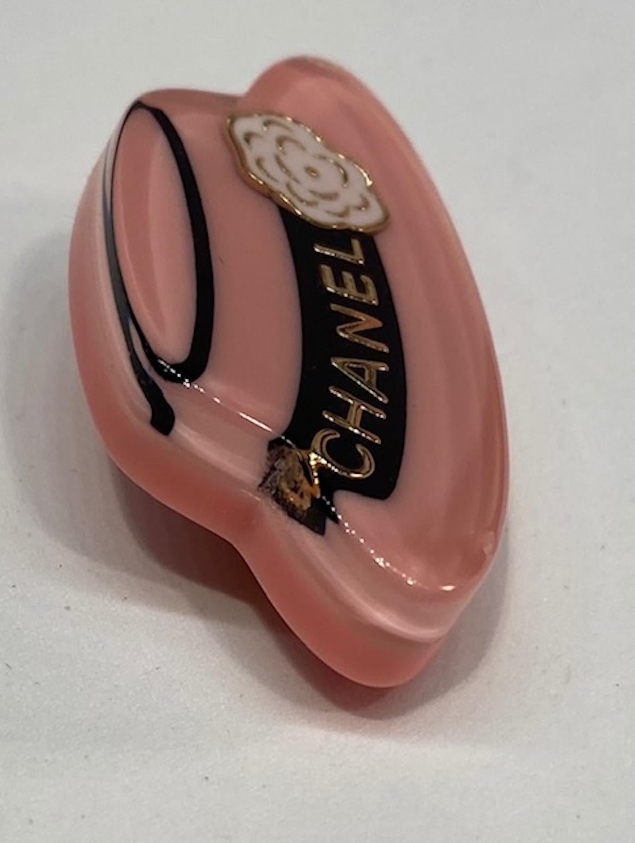 A charming 2018 spring collection lucite brooch of Coco Chanel's famous hat. She had several versions of this brimmed hat for herself and her collections. The lucite is 0.38 thick with the top half in clear and the bottom half in pink lucite.