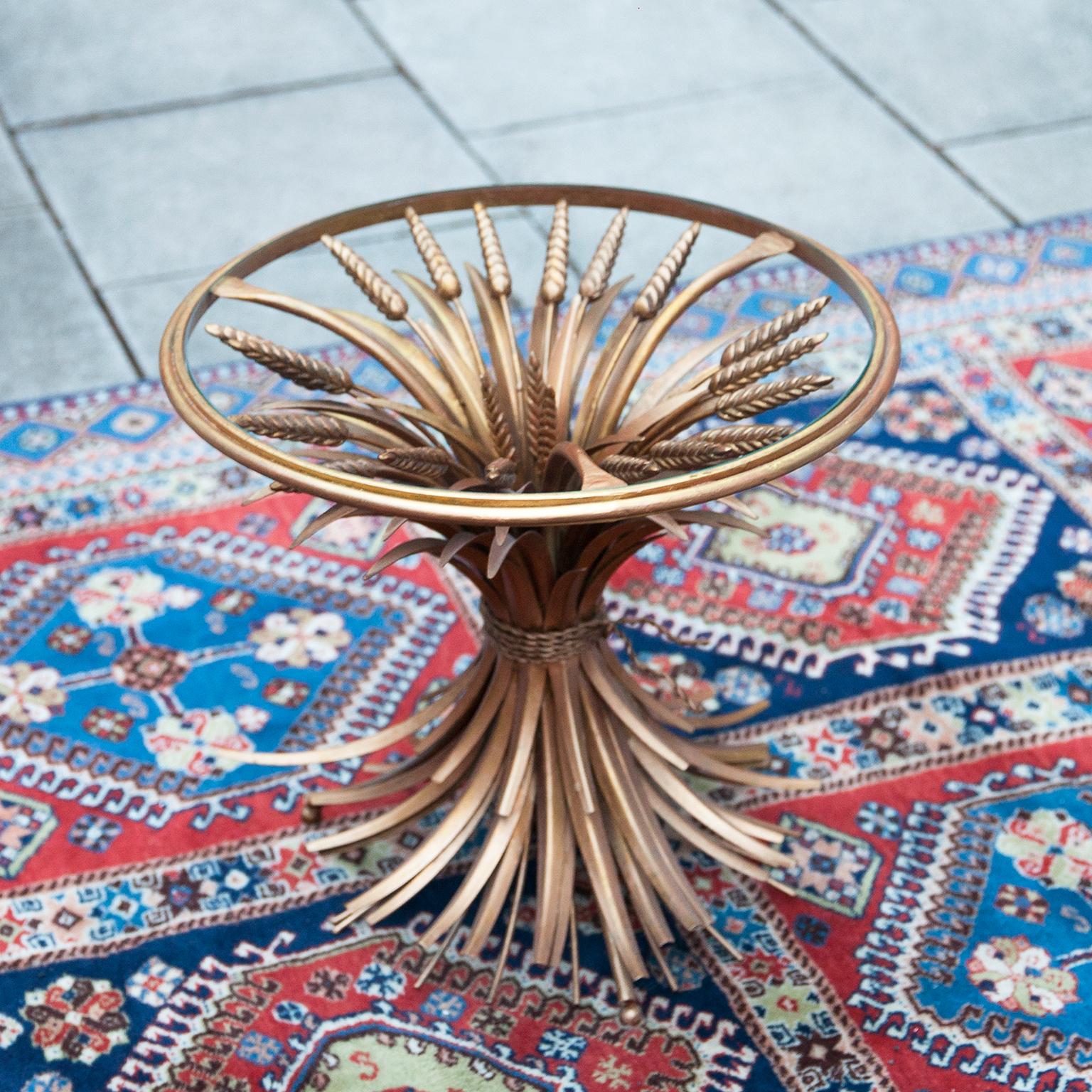 A truly eye-catching original gold-plated metal coffee table. Fashioned in the shape of a wheat sheaf bound by string and a perfect round glass top embossed in a golden metal rim. This table is a really old piece in original shape with the perfect