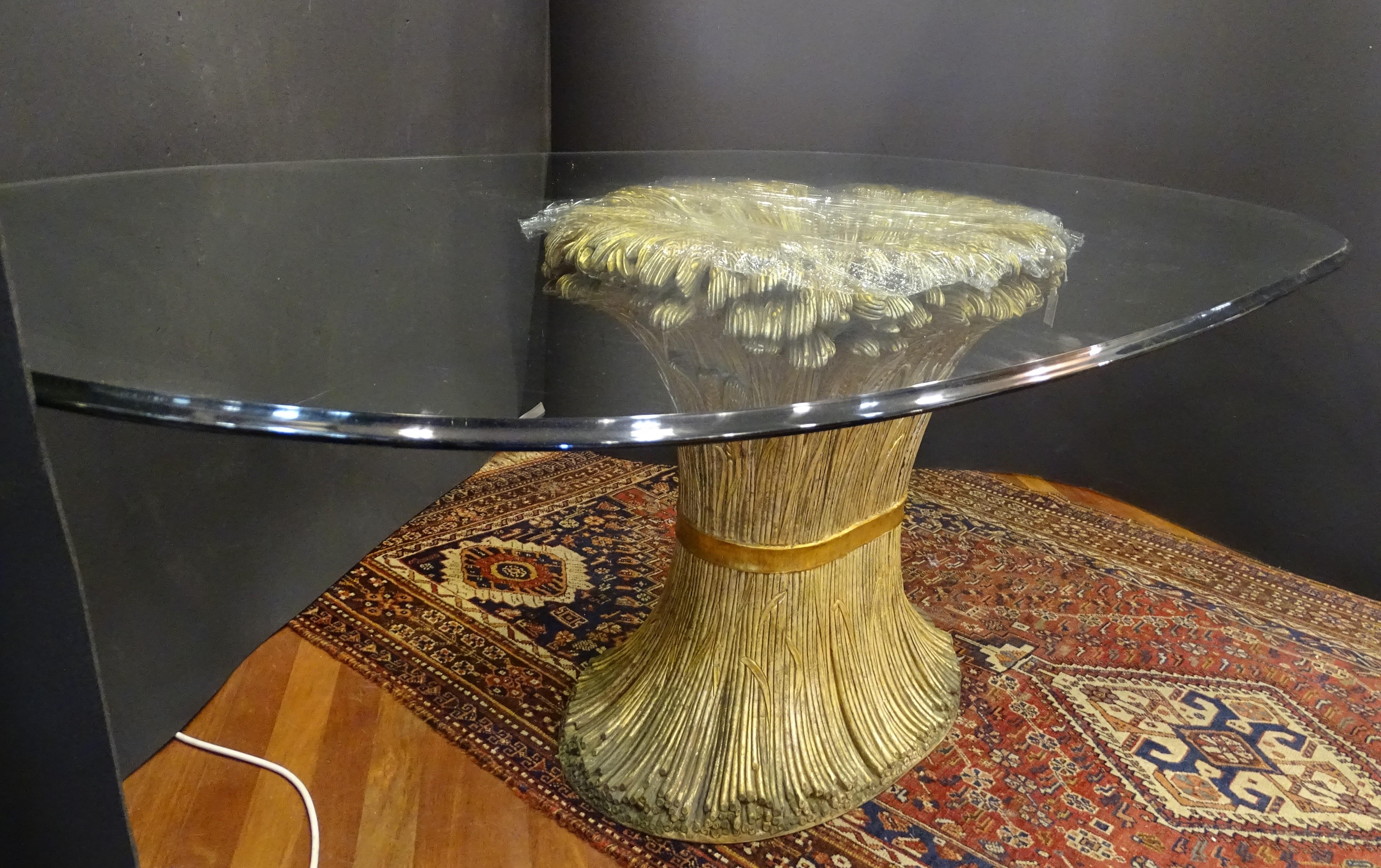 Outstanding Dining table made of gilded carved wood and with a 2 cm oval profile top of beveled glass, 