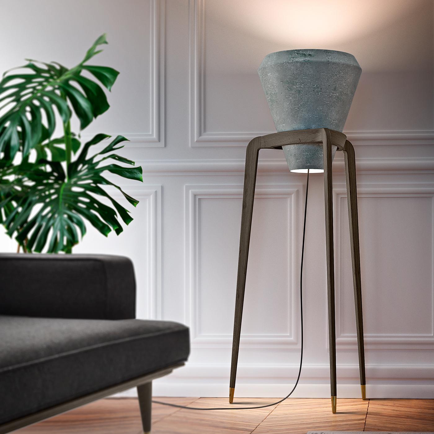 This exquisite floor lamp combines contrasting materials in a unique silhouette of strong visual impact. Its solid durmast structure comprises three tapered legs ending in gold-finished brass tips, while the top forms a ring on which is mounted the
