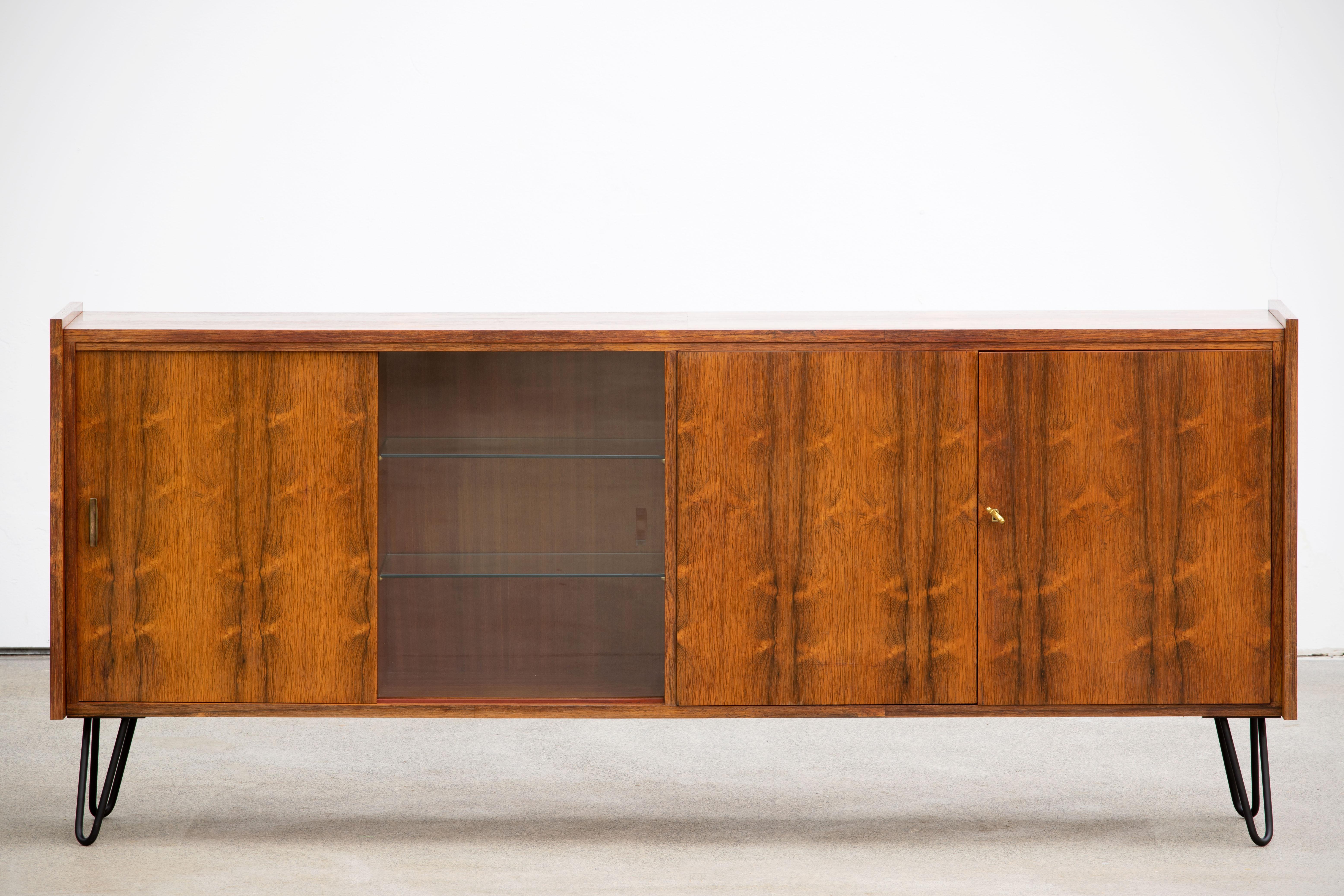 Midcentury sideboard from the 1960s. It is a shining example of the form and function synonymous with furniture of this era. It has is all, well-built, great design and heaviness. Four doors hiding storage space. The minimal design and the warm tone