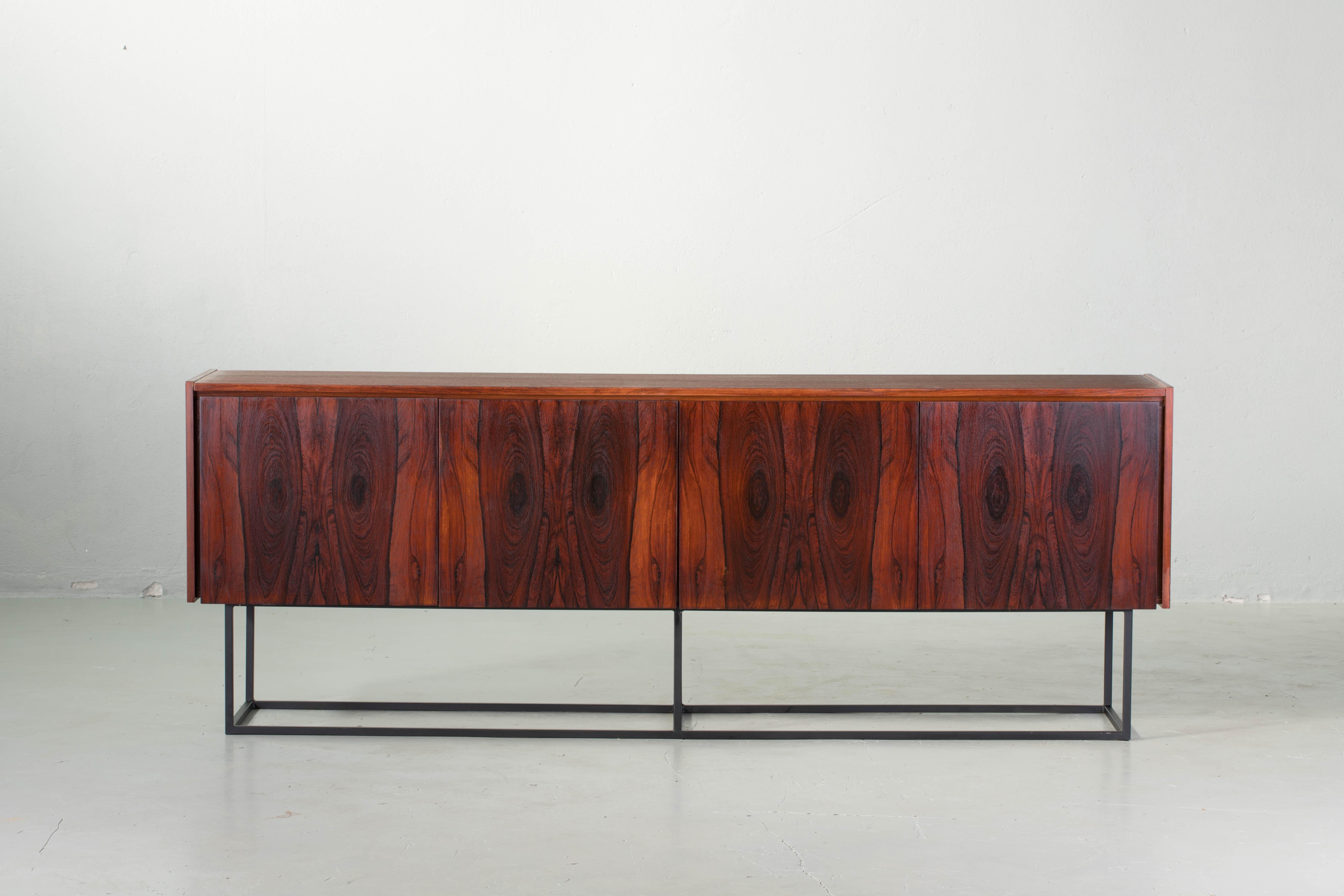 Midcentury teak sideboard from the 1960s. It is a shining example of the form and function synonymous with Bauhaus furniture of this era. It has is all; well-built, great design and heaviness. 
The minimal design and the warm tone combined with the