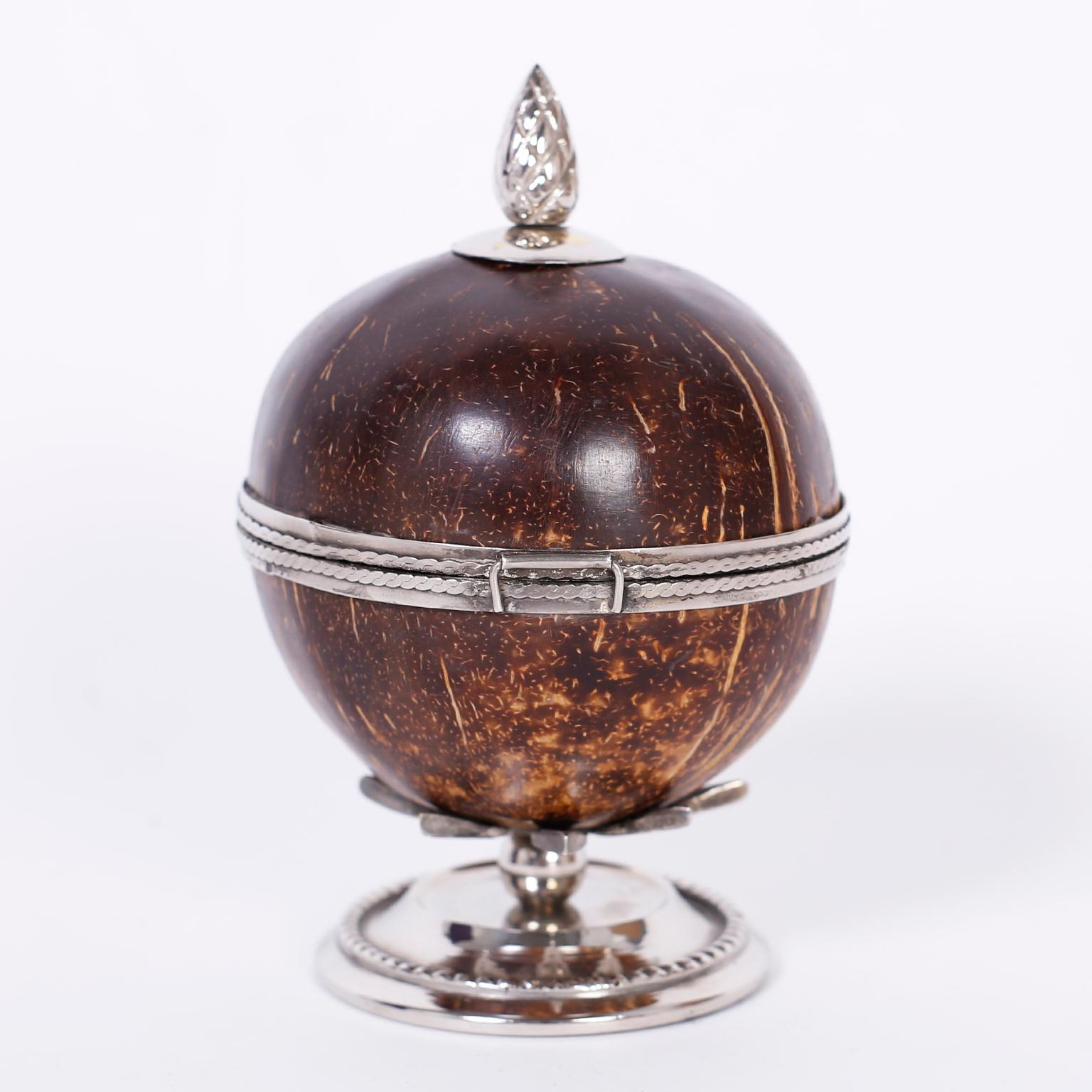 Antique Anglo-Indian trinket box crafted with a polished coconut decorated with silvered metal finial, collars, clasp and stand with jewelry like precision.