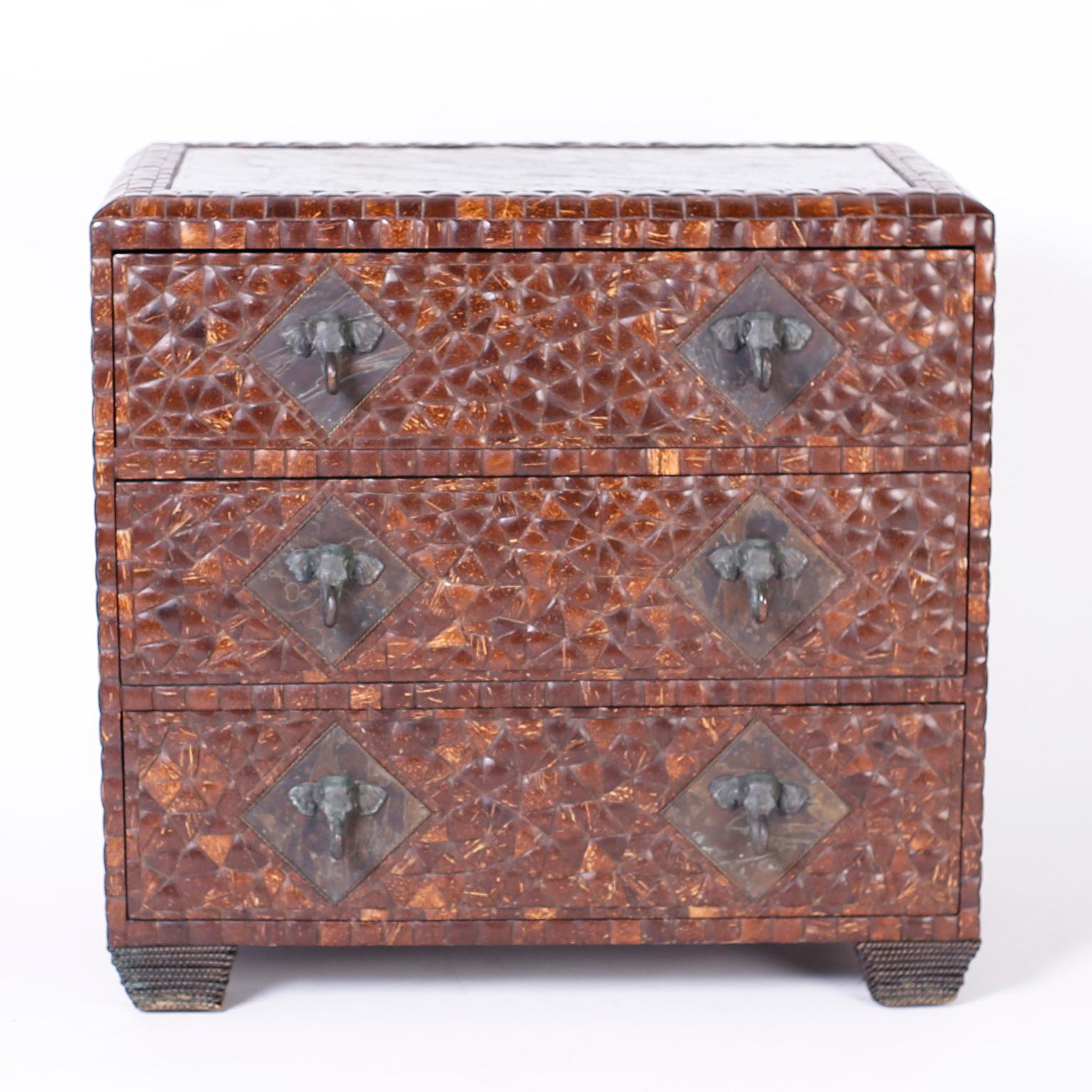 Three drawer chest clad in polished coconut shells featuring bronze panels on the top and sides with embossed biometric designs and bronze elephant head hardware. Signed Maitland-Smith in a drawer.