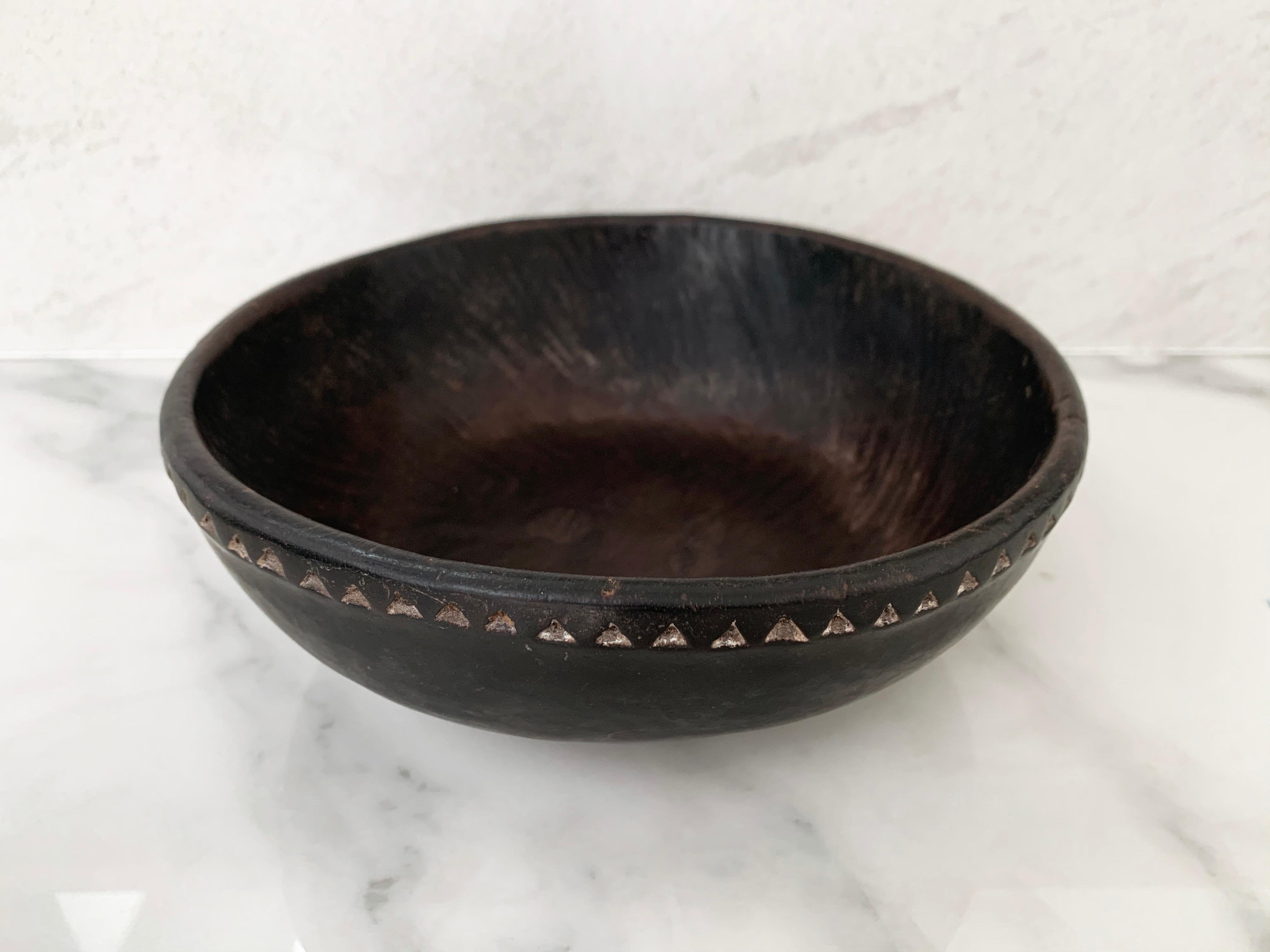 This hand crafted and tribal engraved bowl originates from Nias Island Indonesia. It features tribal motifs along the rim and a beautiful hand hewn texture along its basin. It is crafted from coconut tree wood.
    