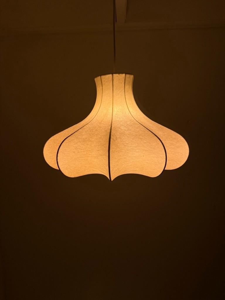 The Cocoon Lamp is a masterpiece of mid-century modern design, celebrated for its innovative use of materials and organic forms. Achille Gastiglioni in collaboration with his brother Pier Giacomo Castiglioni designed the first Cocoon lamps with