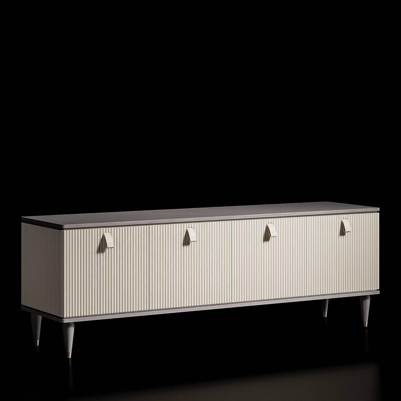 Refined and stately, this elegant sideboard features a rectangular silhouette framed with inlaid veneer in an elegant grey color supported by four conical feet accented with metal ferules in a warm brass finish. The beige-colored central body has