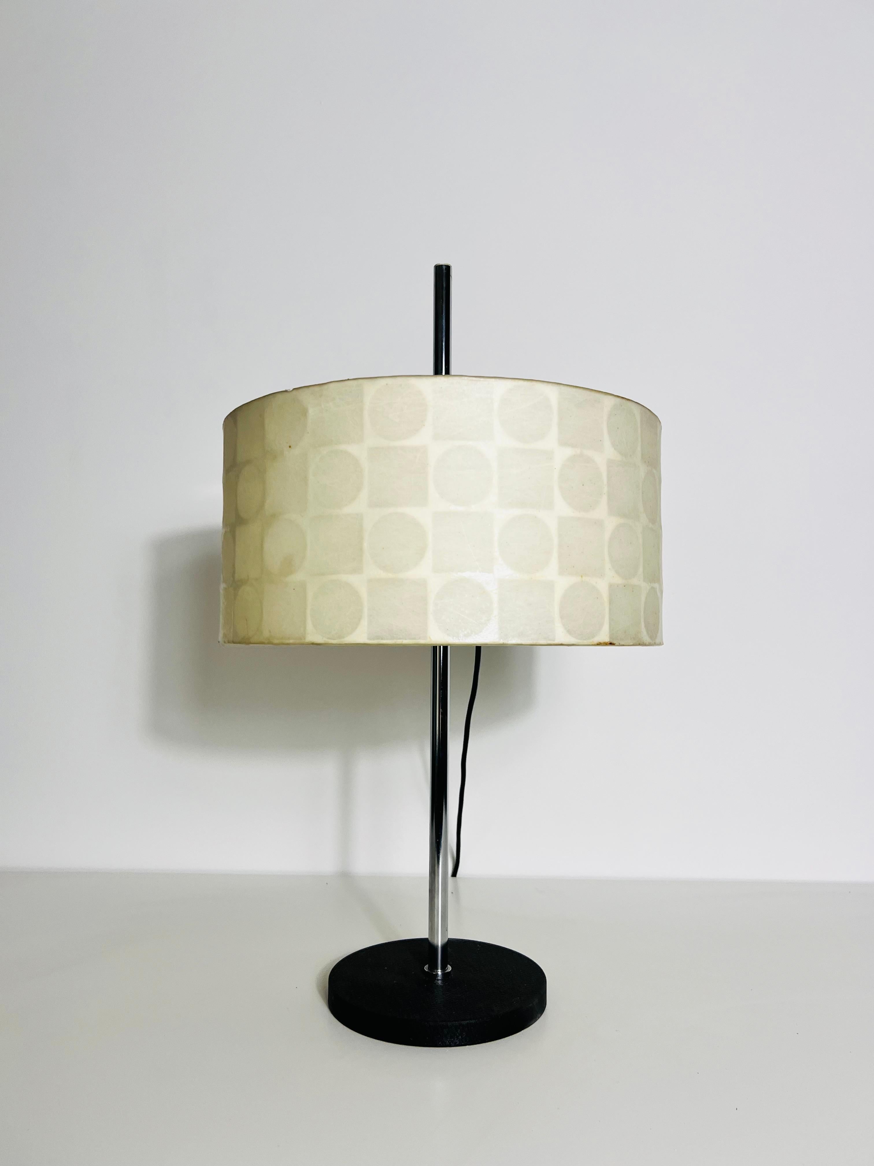 This floor lamp, crafted from dark bamboo wood, features a design where the wood opens upward. At the top, a round opal glass globe is held between the three arms of the wooden stand, giving the appearance that the bamboo structure is cradling the