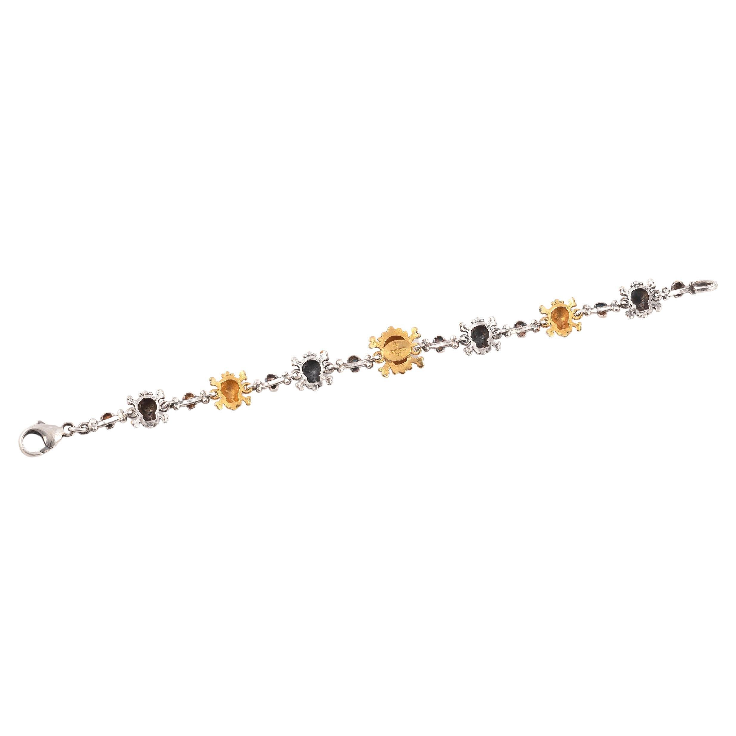 

Designed as a line of seven Memento Mori gold and silver crossed bones skulls, the larger at the centre with diamond eyes, connected by other small skulls and single bone links. 

Mounted in 18Kt gold and silver

Signed A. Codognato