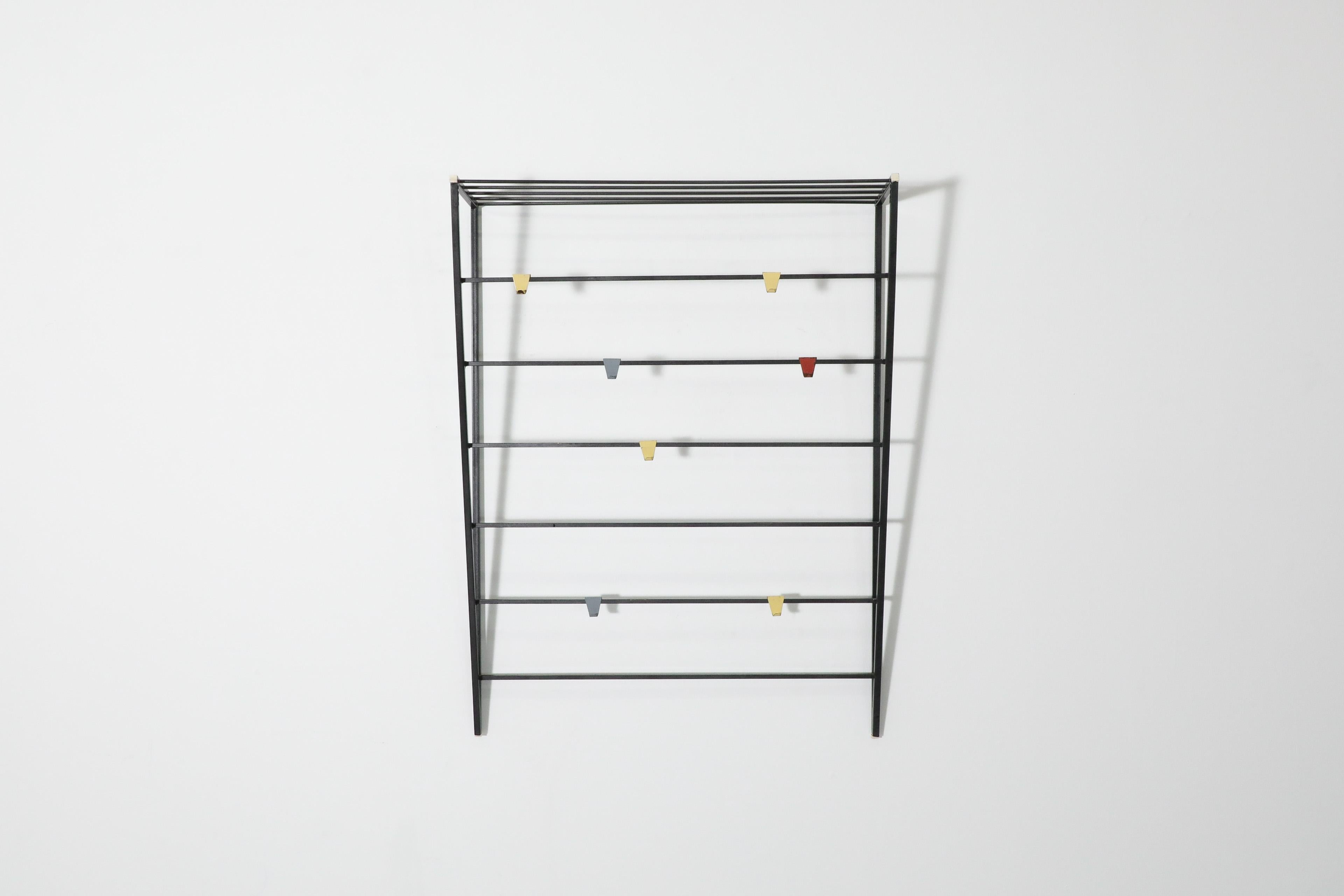 Triangular wall mount coat rack with multi-colored hooks by Coen de Vries for Pilastro. A functional black enameled metal wall mount rack with adjustable hooks and hat shelf. In original condition with visible signs of wear including enamel loss and