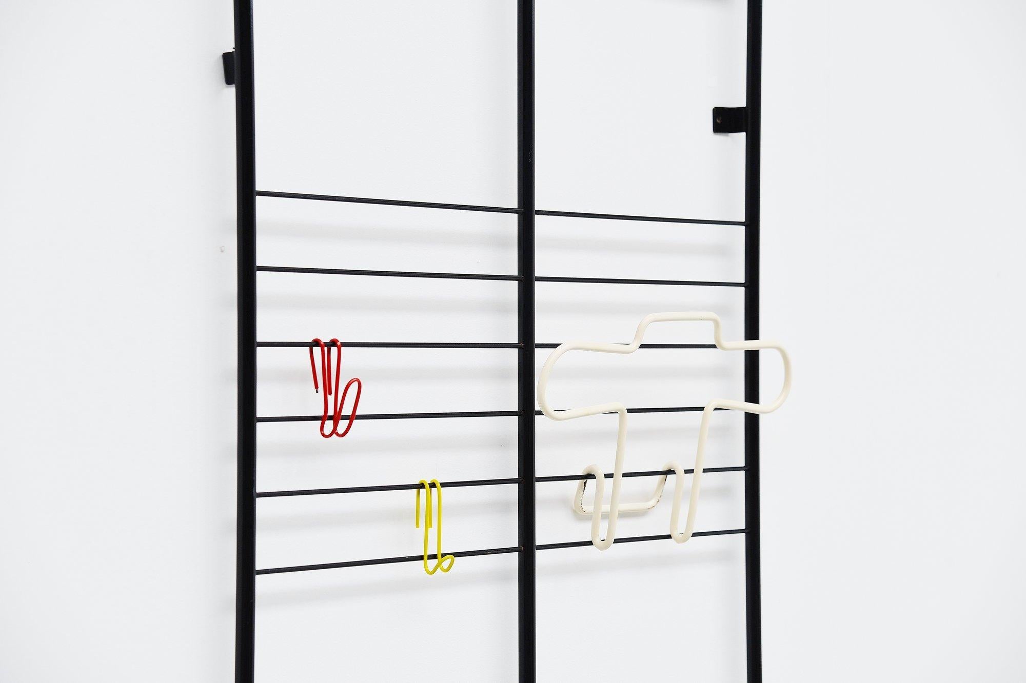 Rare wall-mounted coat rack model GW1 designed by Coen de Vries and manufactured by Devo Den Haag, Holland, 1954. This coat rack has a black painted tubular metal frame and the coat hooks and jacket holder are coated in plastic. The jacket holder is