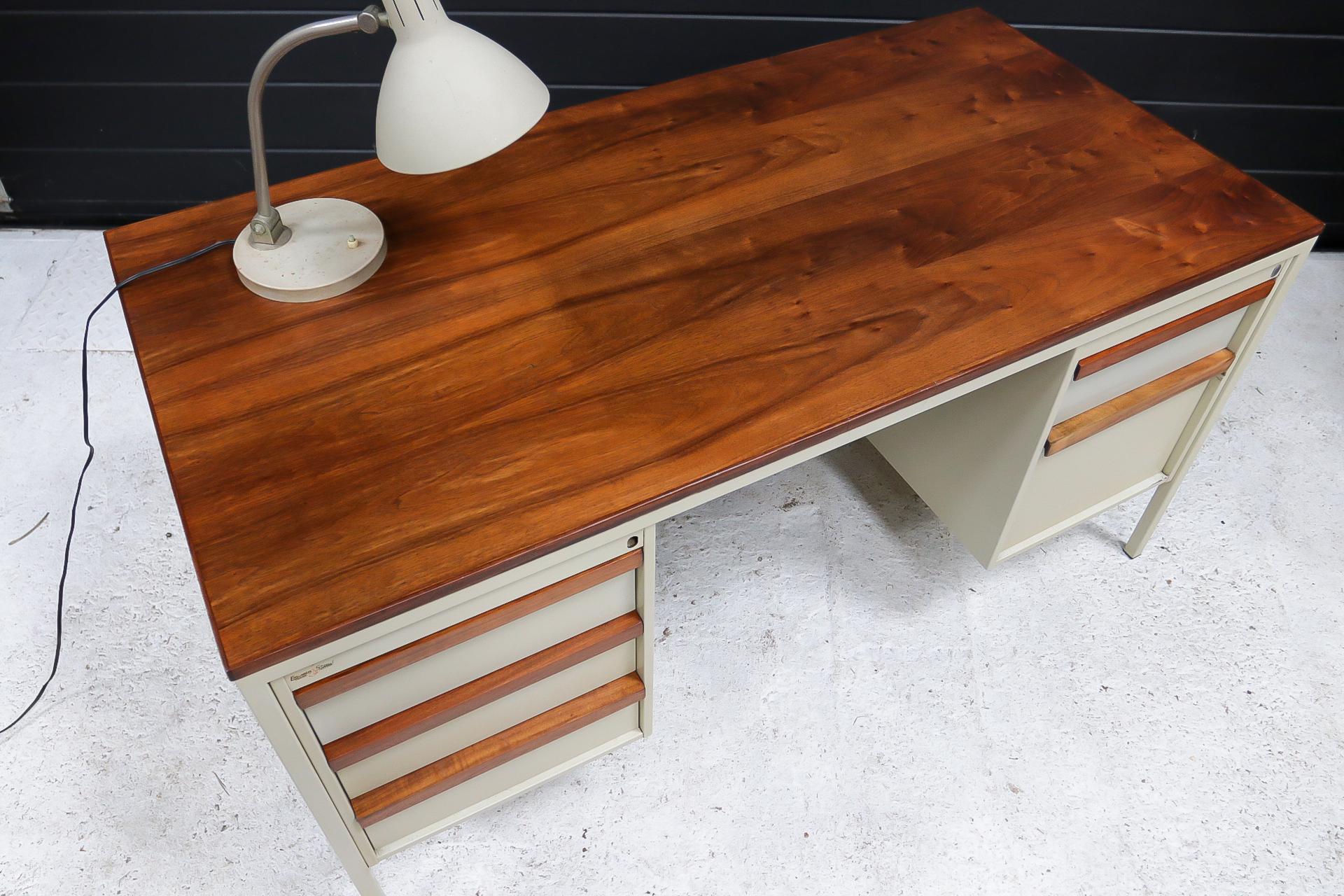Mid-century Coen de Vries industrial metal desk with double stacked drawers.
Beautiful table top, made of a walnut wood type, with matching drawer handles.
The metal frame is coated in a gray color.
The desk dates from around the 1960’s, the desk