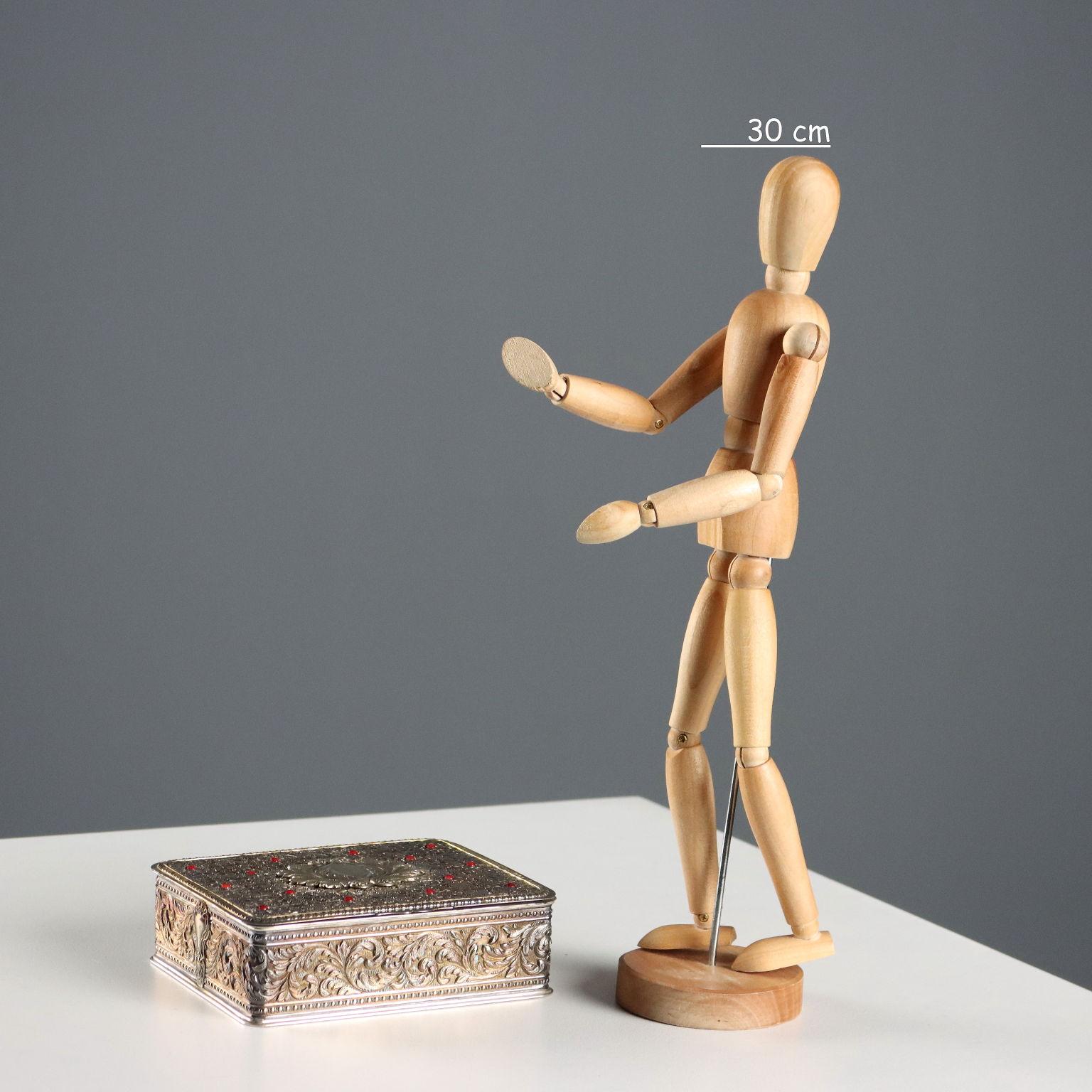 Cofanetto in argento riccamente cesellato e lavorato a bulino con volute fogliacee e motivi ripetuti a riccioli e campanule. Sul coperchio decoro applicato e pietre scarlatte a cabochon. Marchi dell'argento incussi sotto il coperchio. Firma