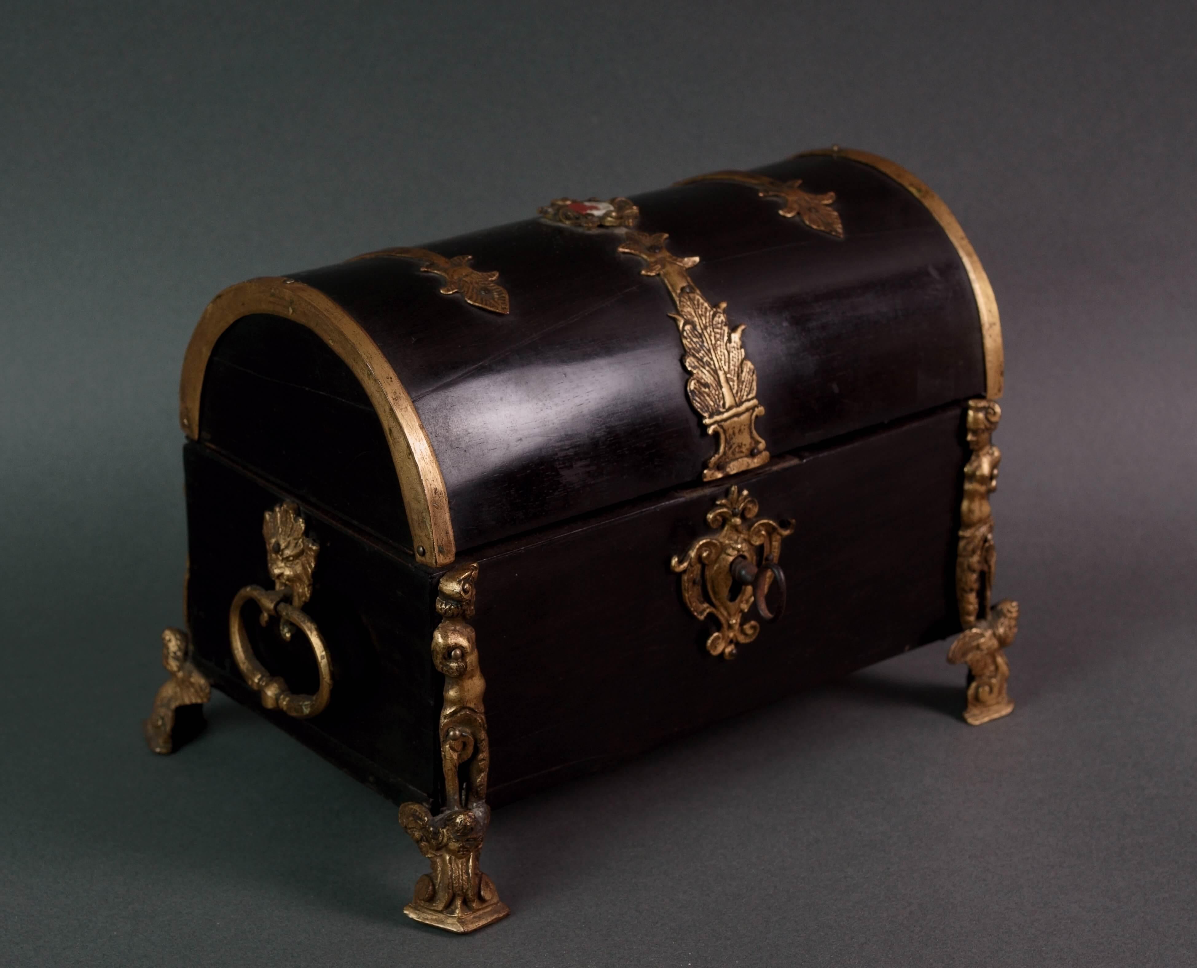 Rara y preciosa caja curva chapada en ébano con rica decoración de bronce dorado y medallón central de jaspe. 
Fabricación renacentista italiana de principios del siglo XVII.

La producción de cajas de maderas preciosas enriquecidas con decoraciones