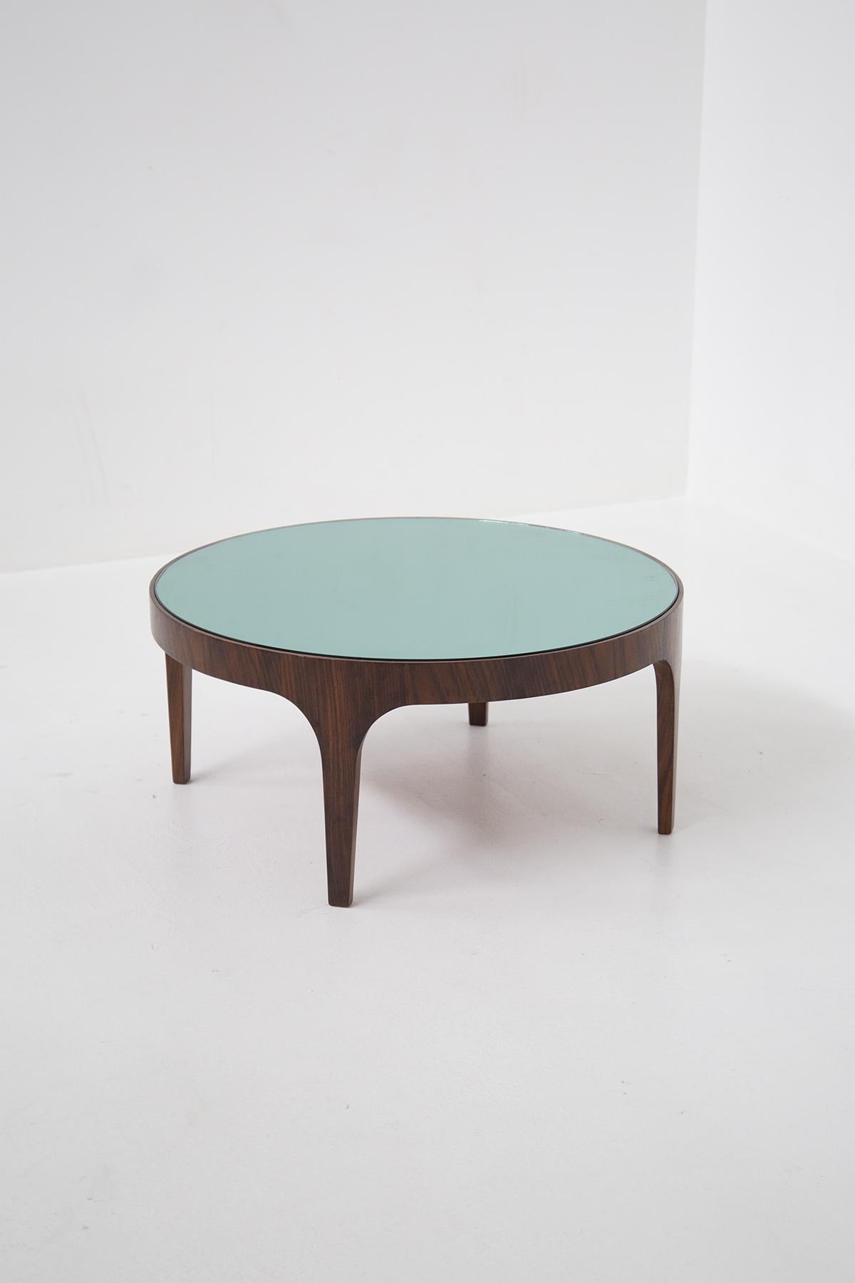 A rare and exceptionally pure round coffee table Model 1774 by Max Ingrand for Fontana Arte, manufacturer's label. In wood with a circular top in sky-blue mirrored glass, resting on an elegantly curved base raised on tapered legs. This table by