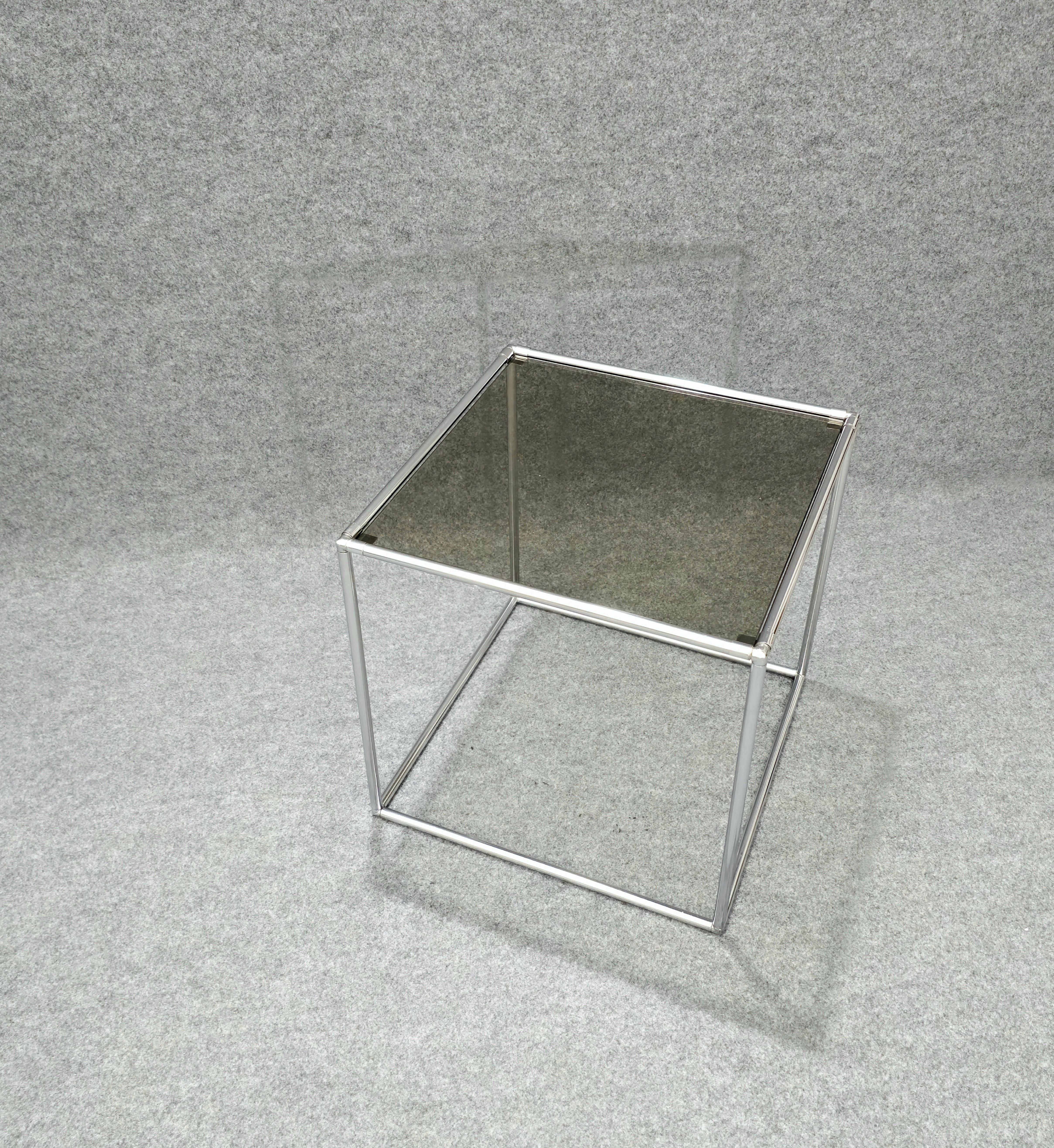 Mesa de centro tubular de metal cromado con 1 estante de cristal ahumado. Fabricado en Italia en los años 70.El cristal se asienta sobre 4 soportes, lo que facilita su extracción y limpieza. Fácil de mover y colocar, adecuado para cualquier entorno.