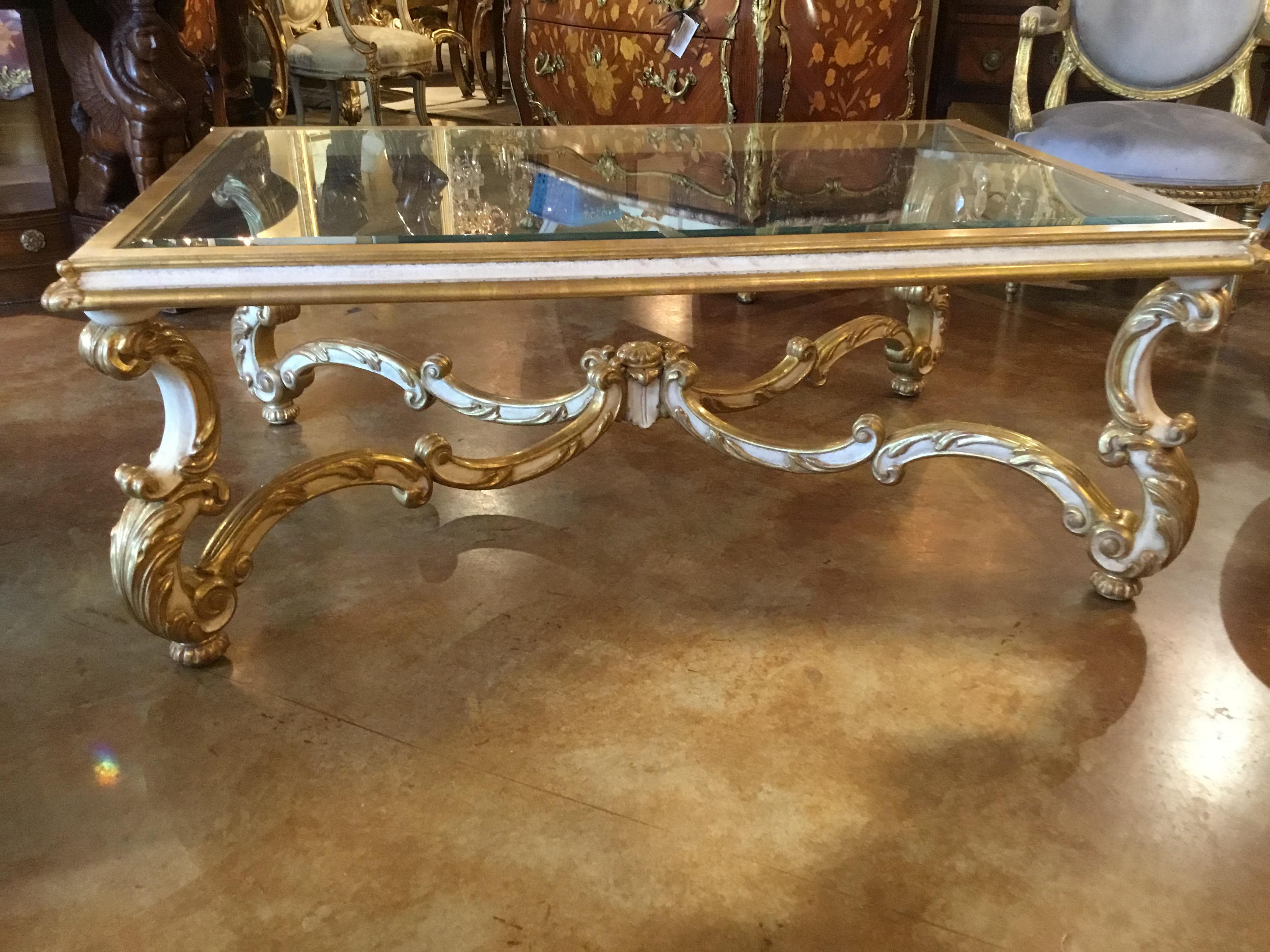 French Louis XV style cocktail table in giltwood and cream paint.
Whorl foot and curved leg support beveled glass.