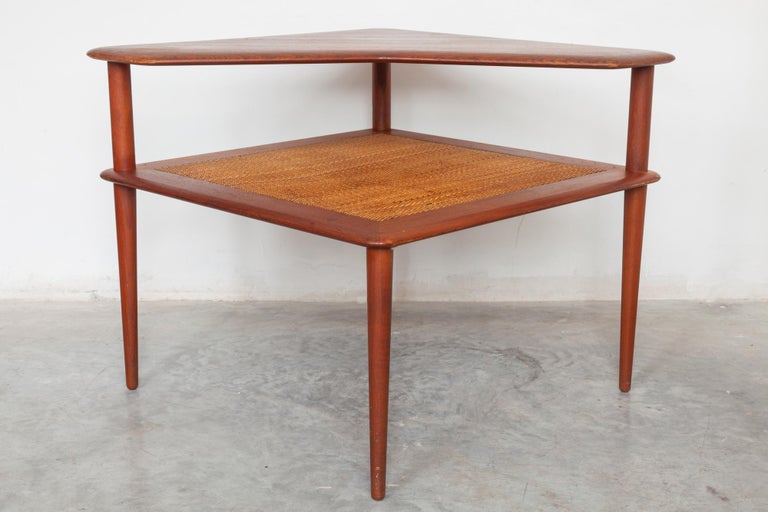 Midcentury teak corner table with woven rattan shelf. Excellent for use as a side
table or sofa table manufactured by France and Sons designer Peter Hvidt.