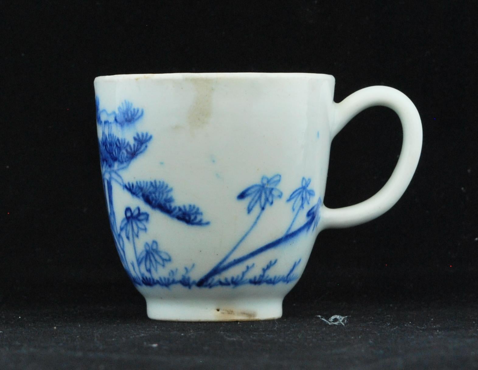 Of Chinese export form with loop handle; the body imaginatively painted in a bright ‘early blue’ underglaze with pine, rock and bamboo after the Chinese. Yellow tinged body; clear glaze with some blue bleeding to glaze and black speckling.