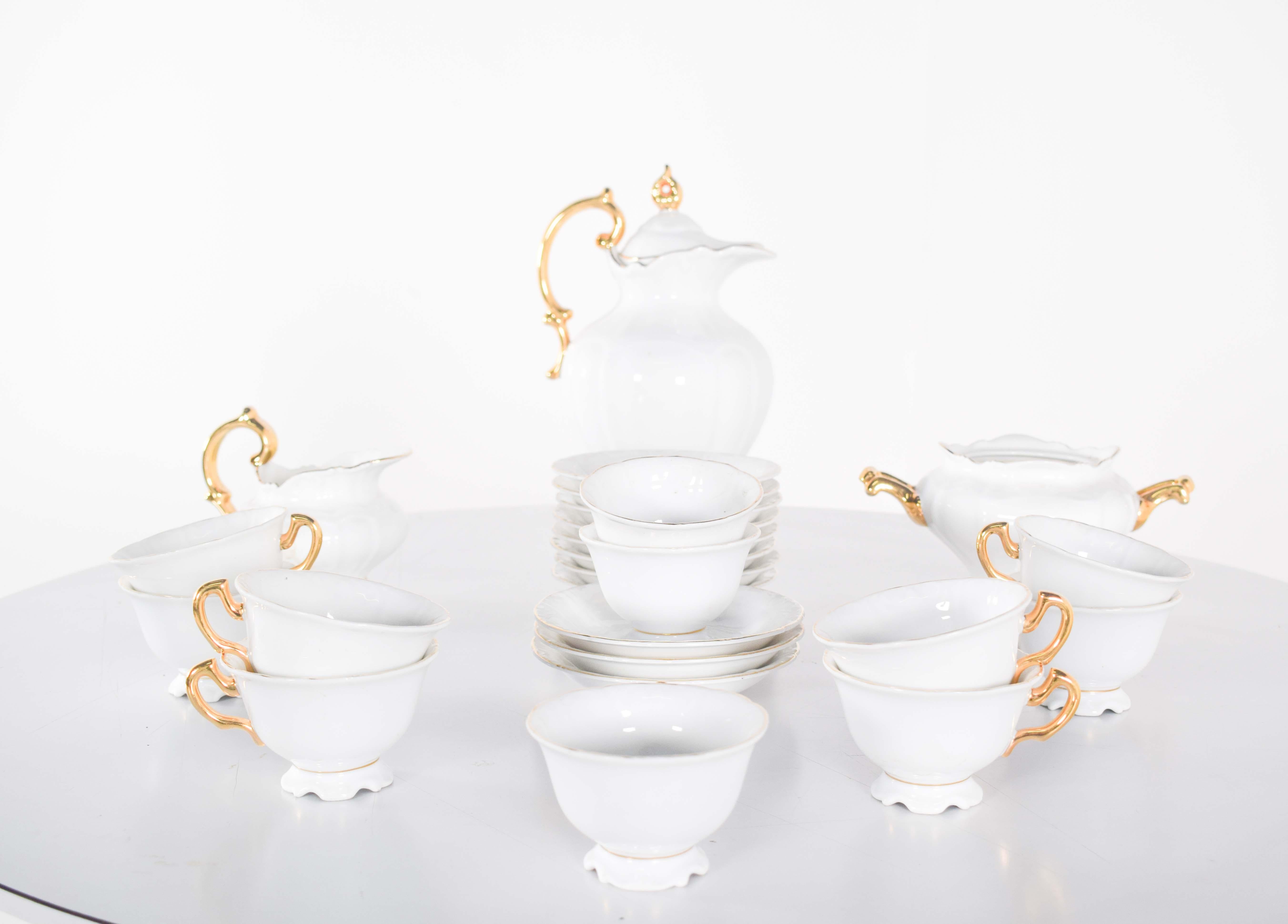 Servizio da caffè completo, in porcellana di Vista Alegre, composto da teiera, lattiera, zuccheriera, dieci piattini e undici tazze. Decorato in oro su bianco sui manici e sul coperchio della teiera.
Il pezzo forte del servizio è la teiera, che si
