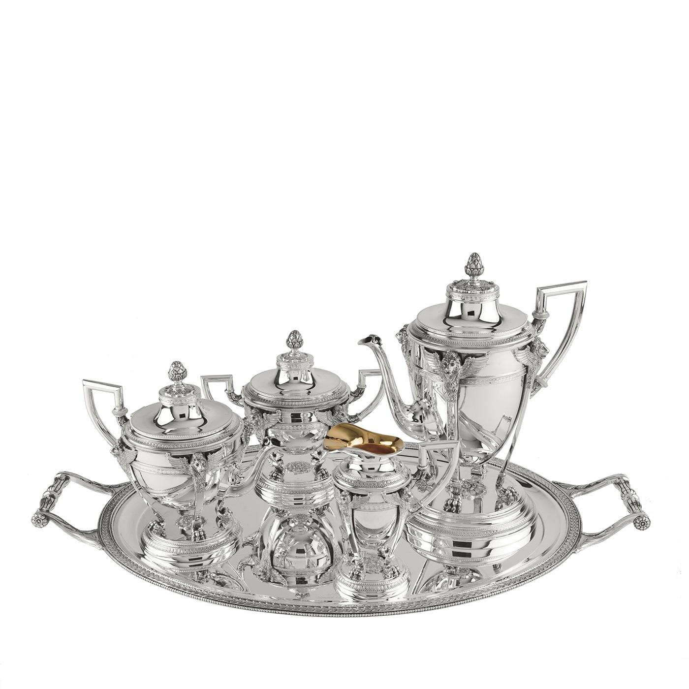 This sophisticated coffee set entirely made in silver will bring a touch of lavish elegance to any table. It is accompanied by an oval tray with rectangular ornate handles and a delicate decoration that runs throughout its edges, inspired by the