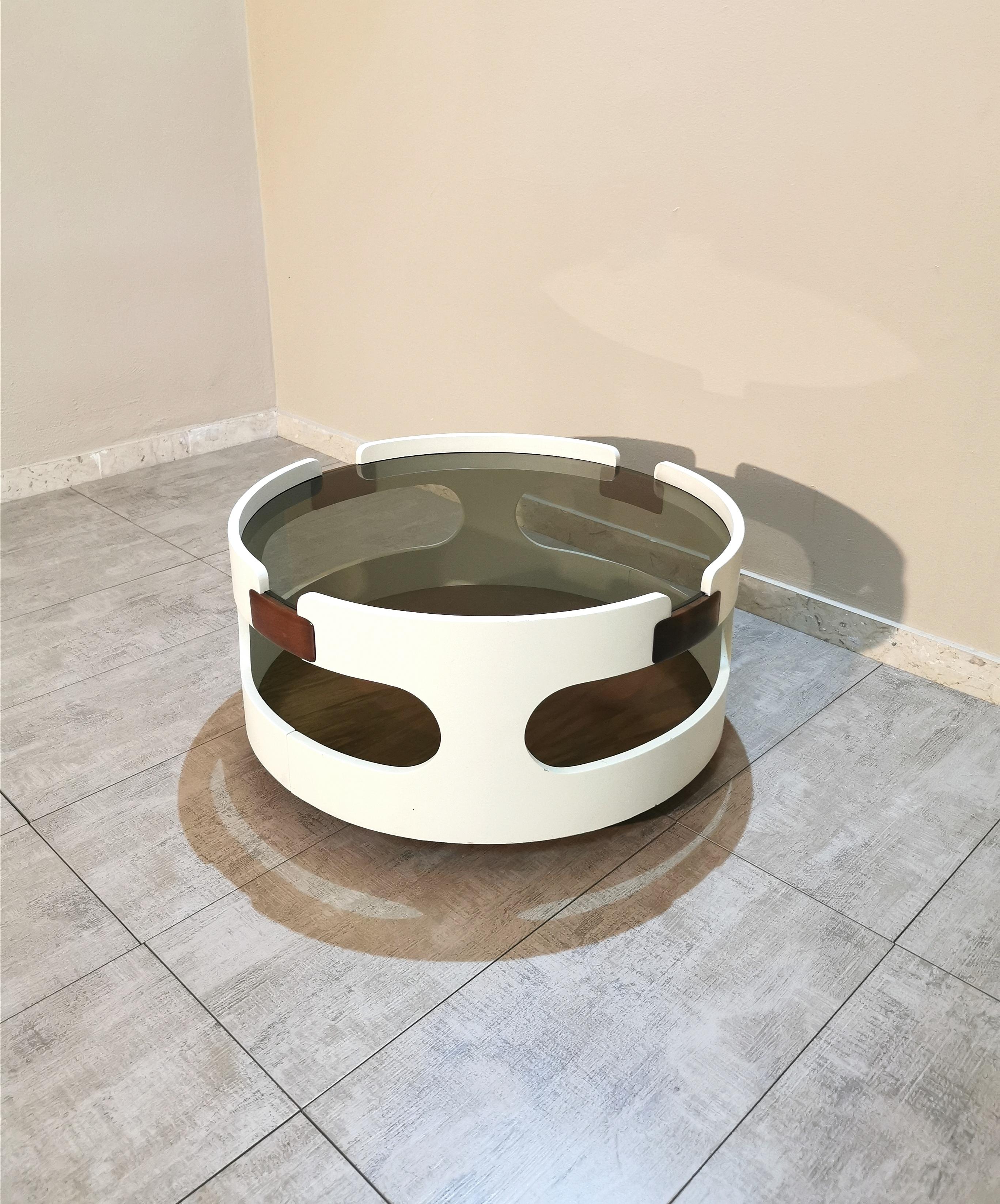 Round coffee table by an unknown designer in white and brown enamelled wood with 2 shelves, where a smoked glass is set in the upper one. Made in Italy in the 70s.