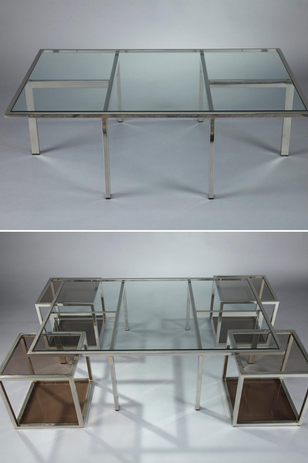 Coffee table in chromed metal and glass dating from the 1970s. The main glass and chromed metal table is rectangular and holds 4 other square side tables that slide into compartments in the four corners of the coffee table. The glass of the 4 side