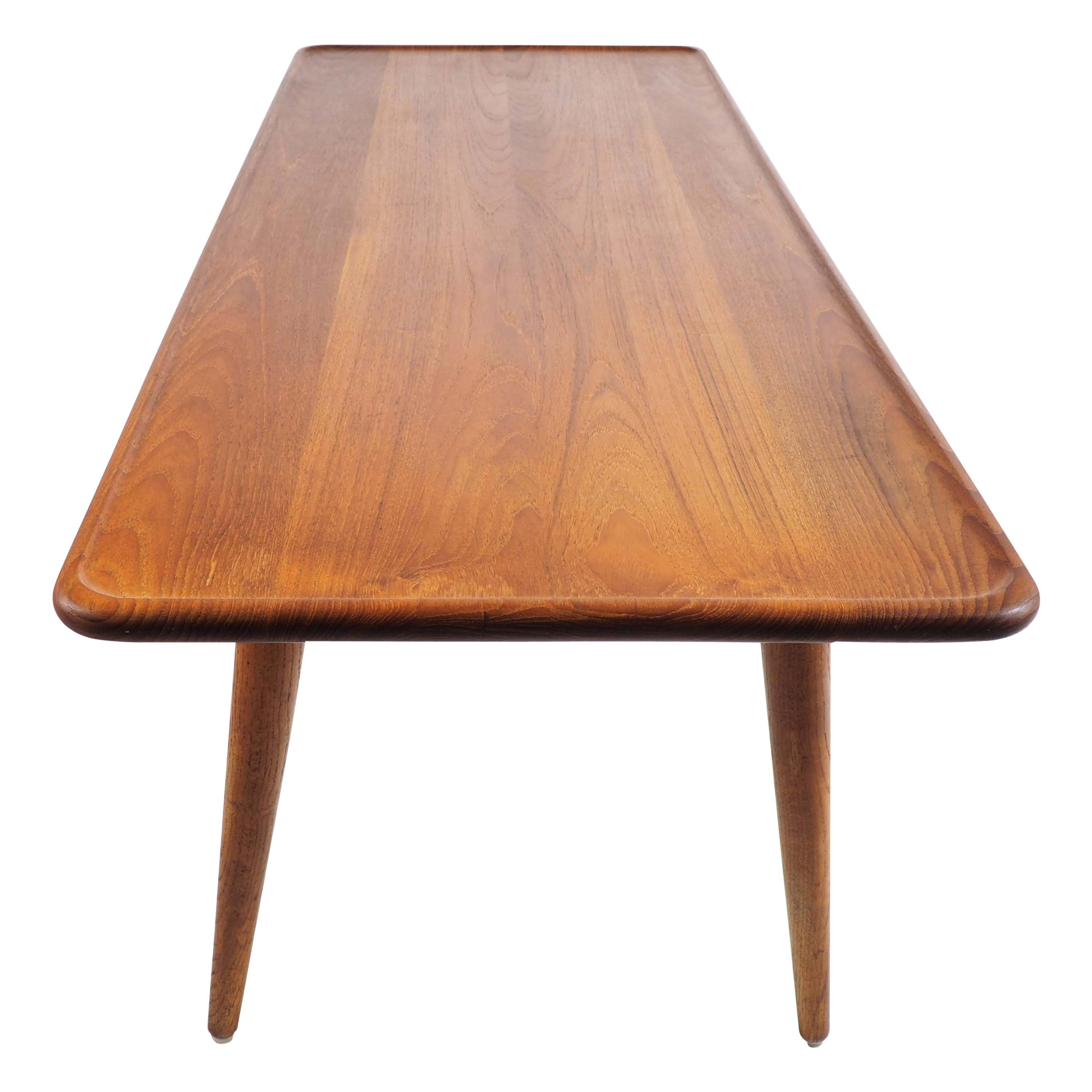 This high quality coffee table was designed by Hans Wegner in the 1950s. It was produced and marked by cabinet maker Andreas Tuck, Denmark, and made with a tabletop in solid teak and legs in solid oak.
The sculptured lip and the rounded corners