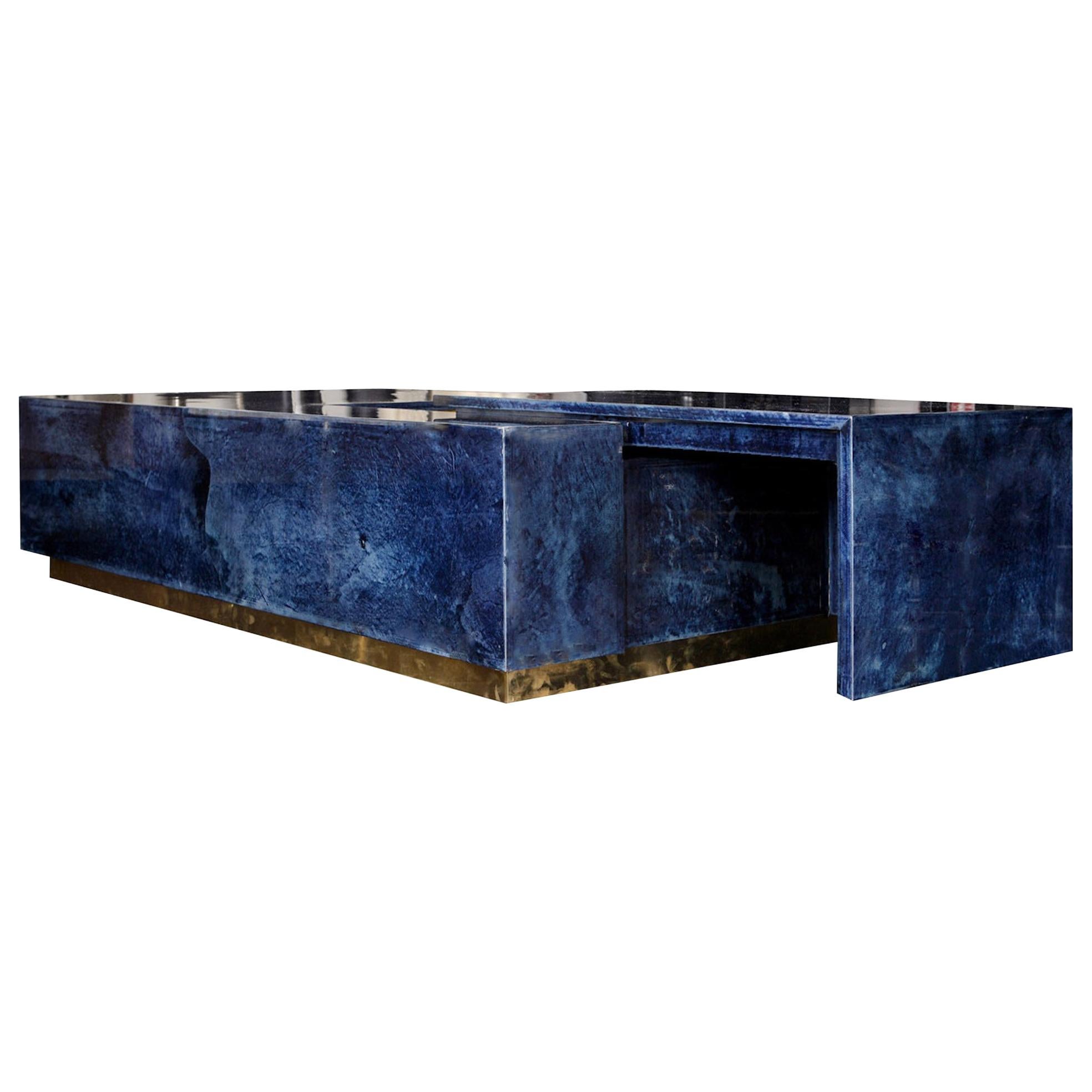 Charming Italian coffee table bar 1970s style, in color Lapis Lazuli Blue parchment goatskin leather finished high gloss, featuring a sliding top and a section underneath (bar) that is covered with brass. 
Top slides through two rails placed