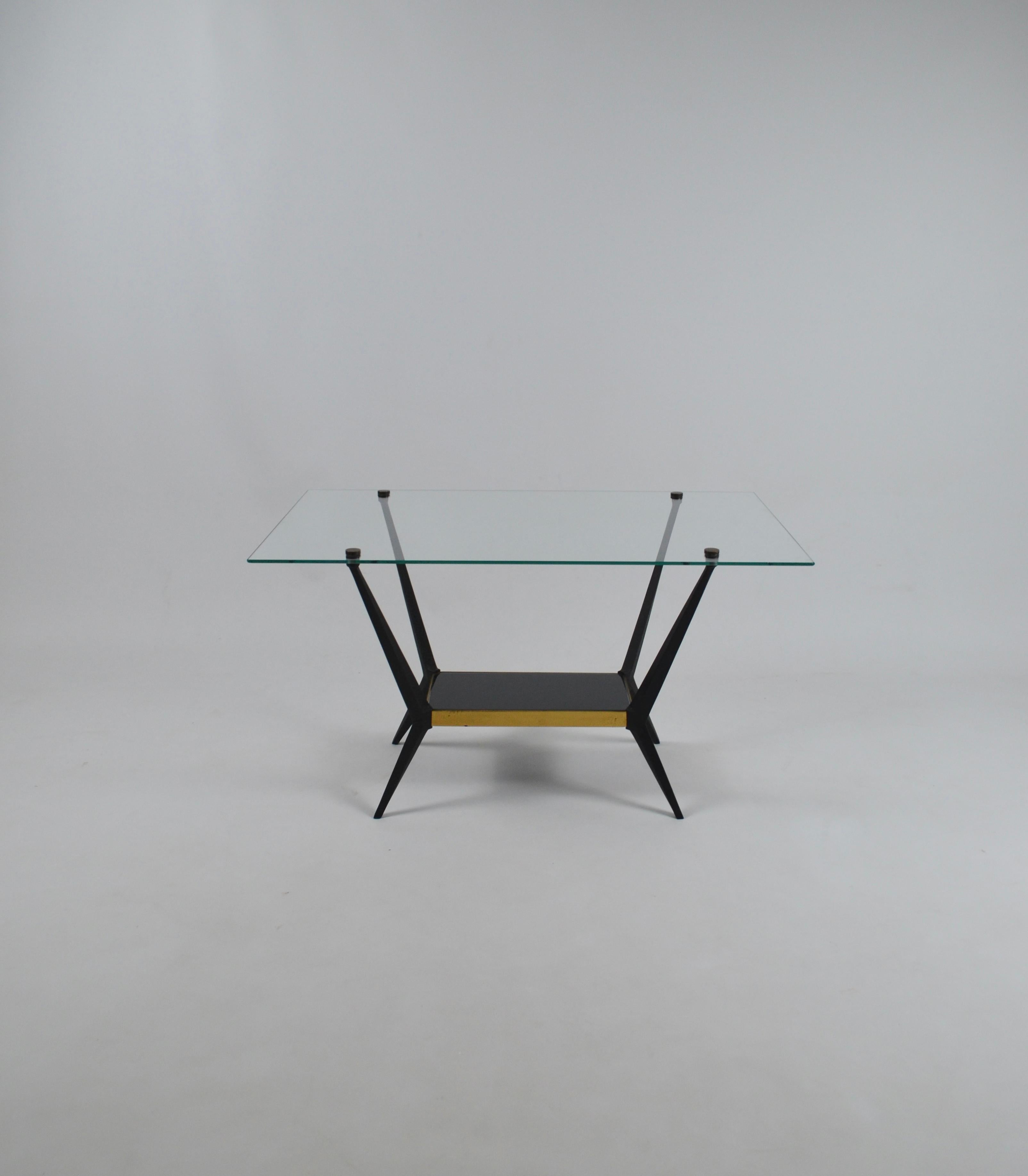 Table basse élégante d'Angelo Ostuni, années 1950.
Il est composé d'une base en métal laqué noir.  La partie inférieure est un plateau en verre noir reposant sur un cadre en laiton doré.  Plateau supérieur en verre fixé à la structure par des