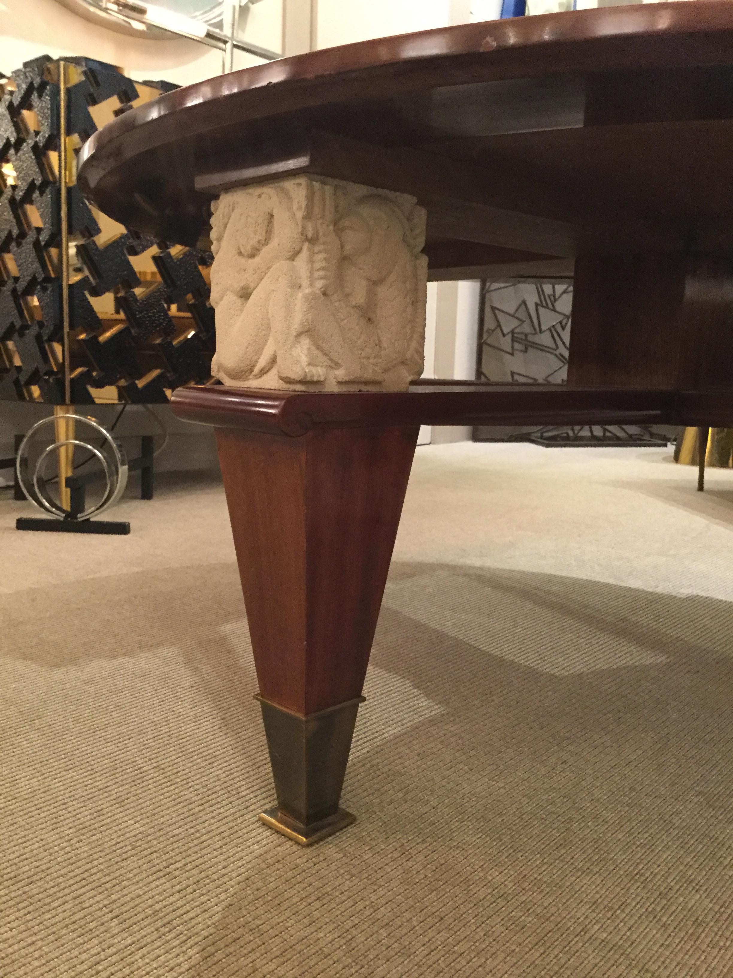 Mahogany with gilt bronze trim and an inset glass tablet top, raised on four tapered and square legs with bronze sabots, headed with limestone carvings and braced with an X-form crossbar.
